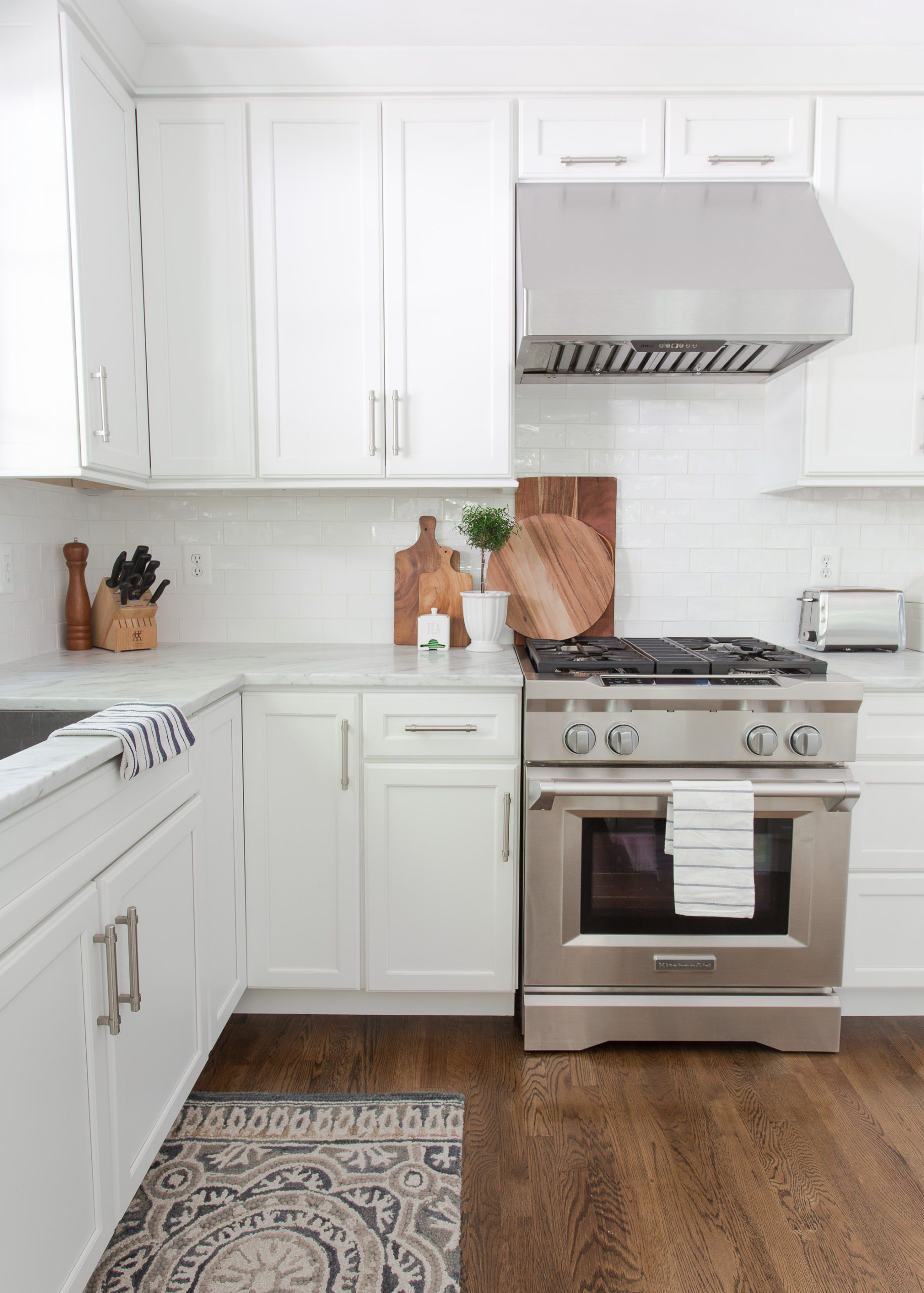 White kitchen with wood floors, stainless steel range
