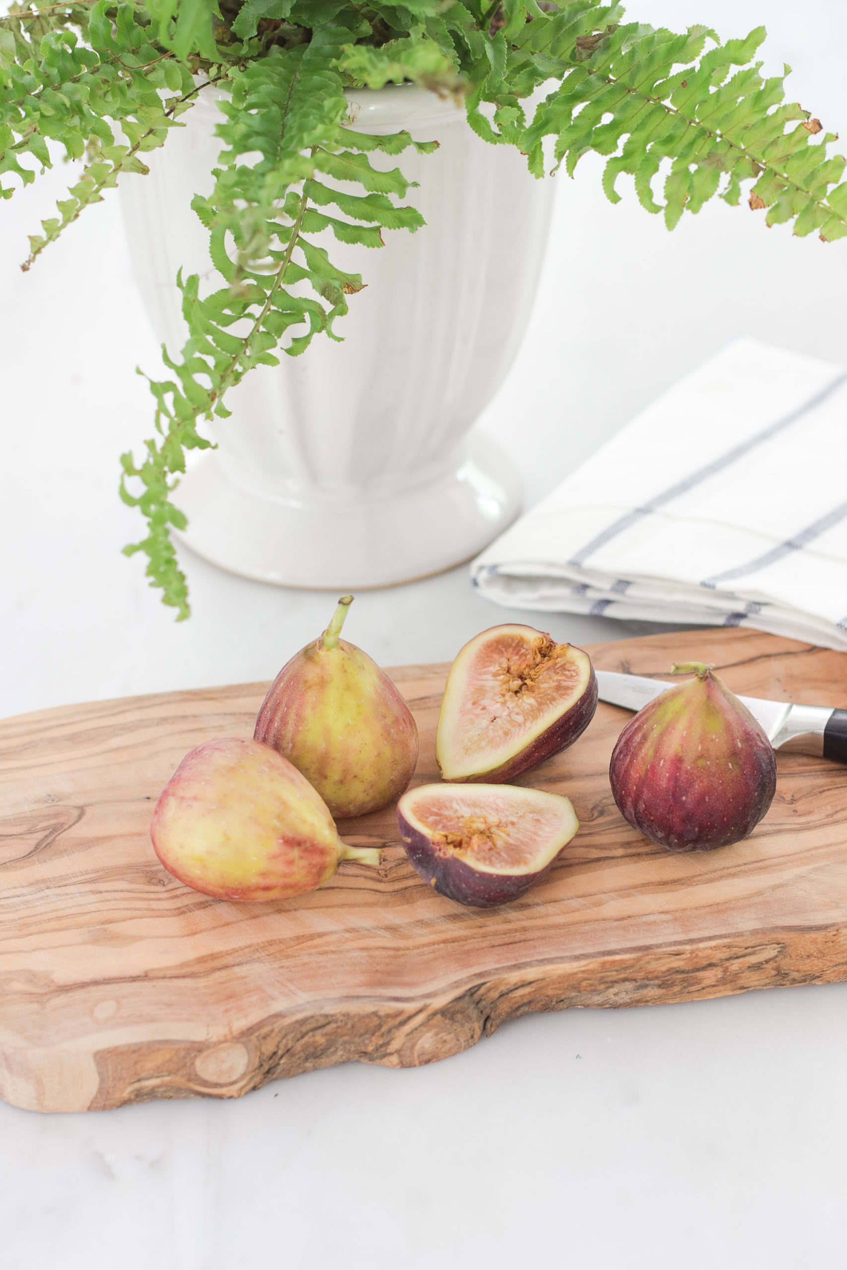 wooden cutting board with cut figs sitting on a marble countertop