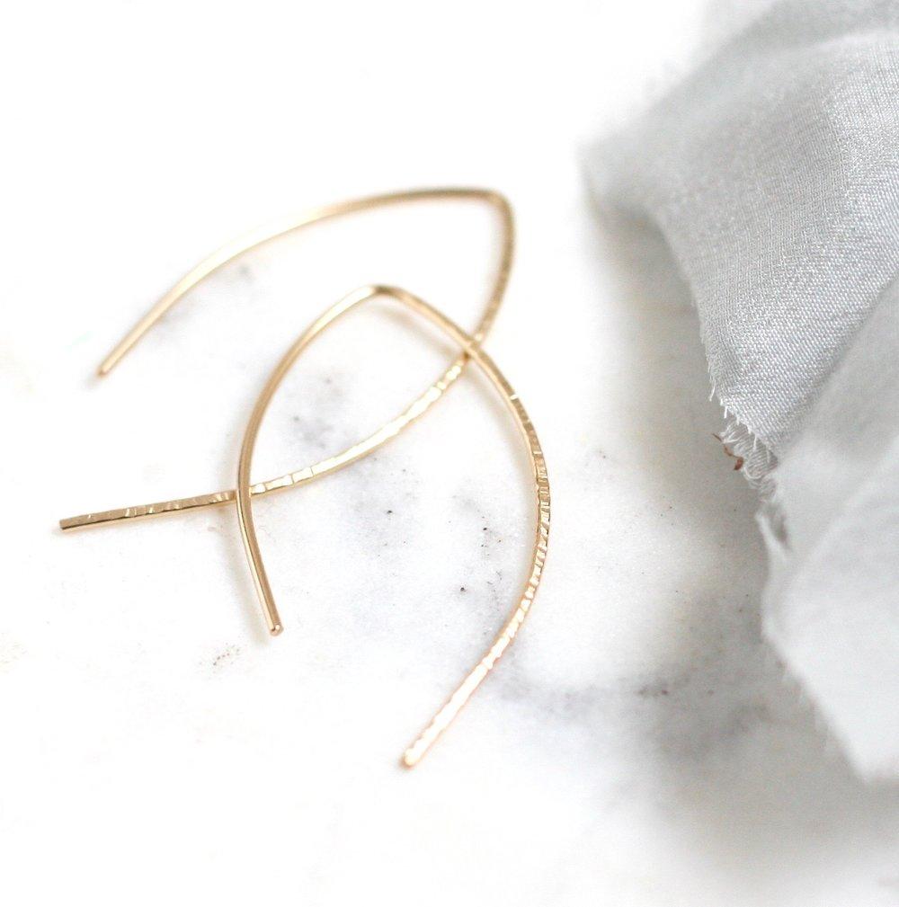 hammered gold arch earrings laid out on marble
