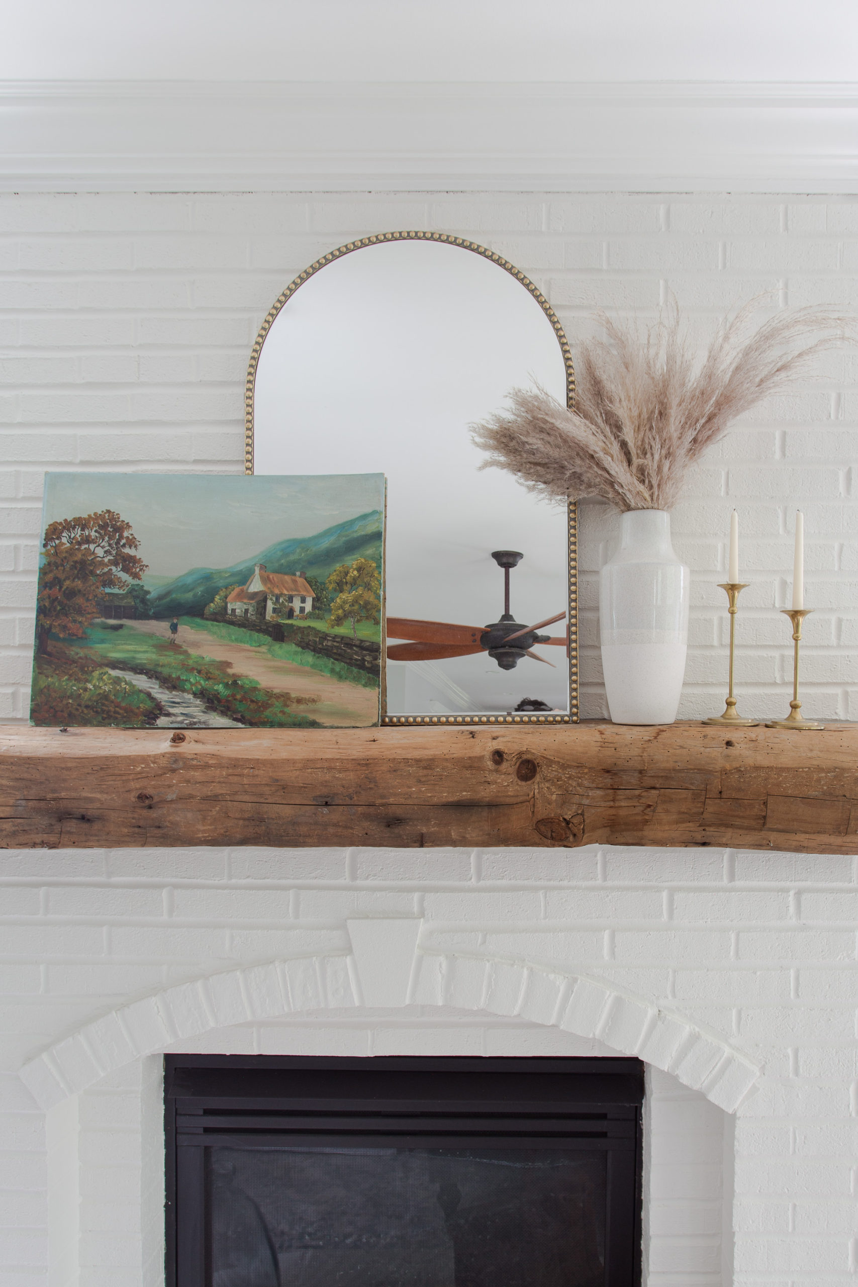 white brick fireplace with mantel mirror and fall painting