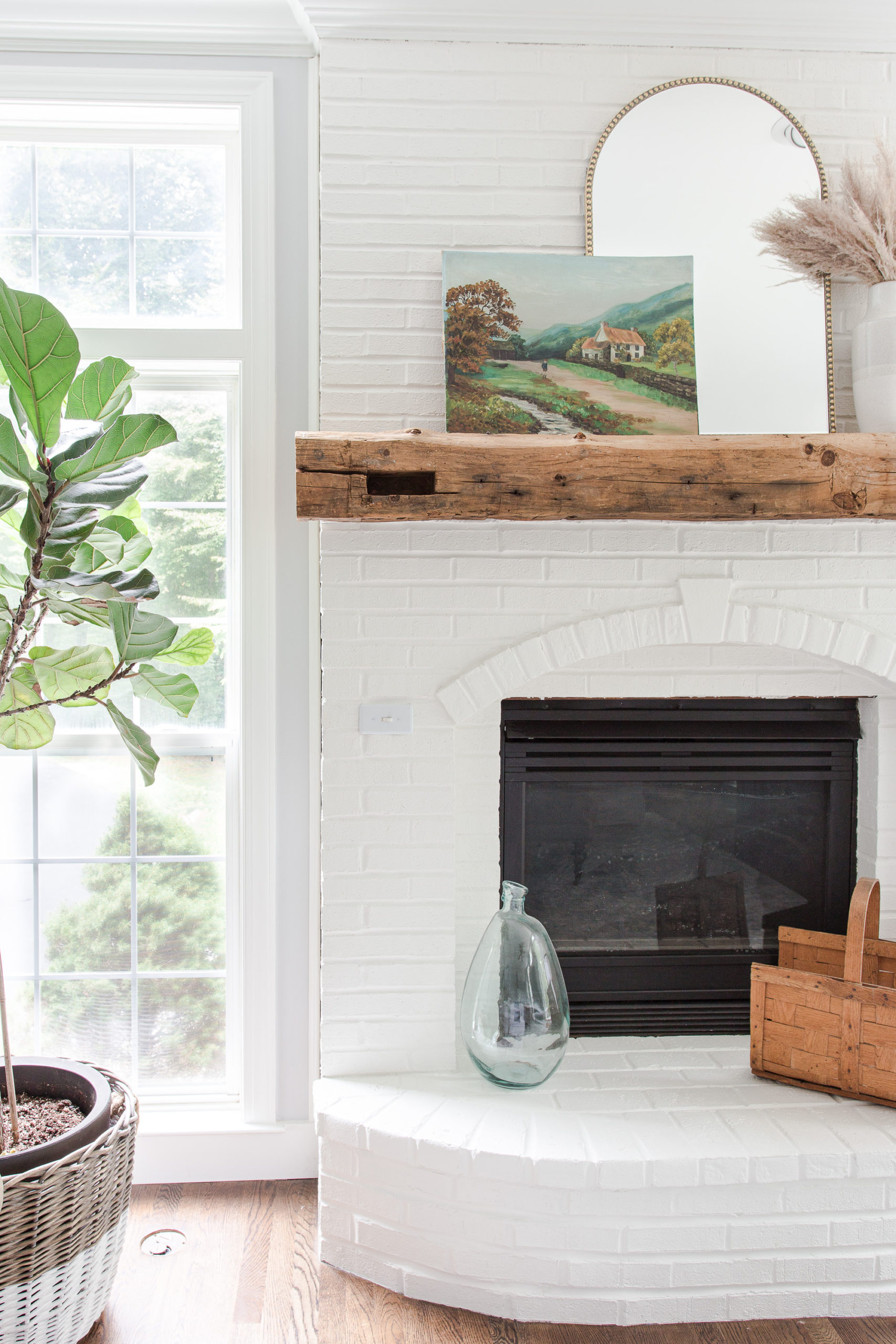 white brick fireplace with mantel mirror and fall painting