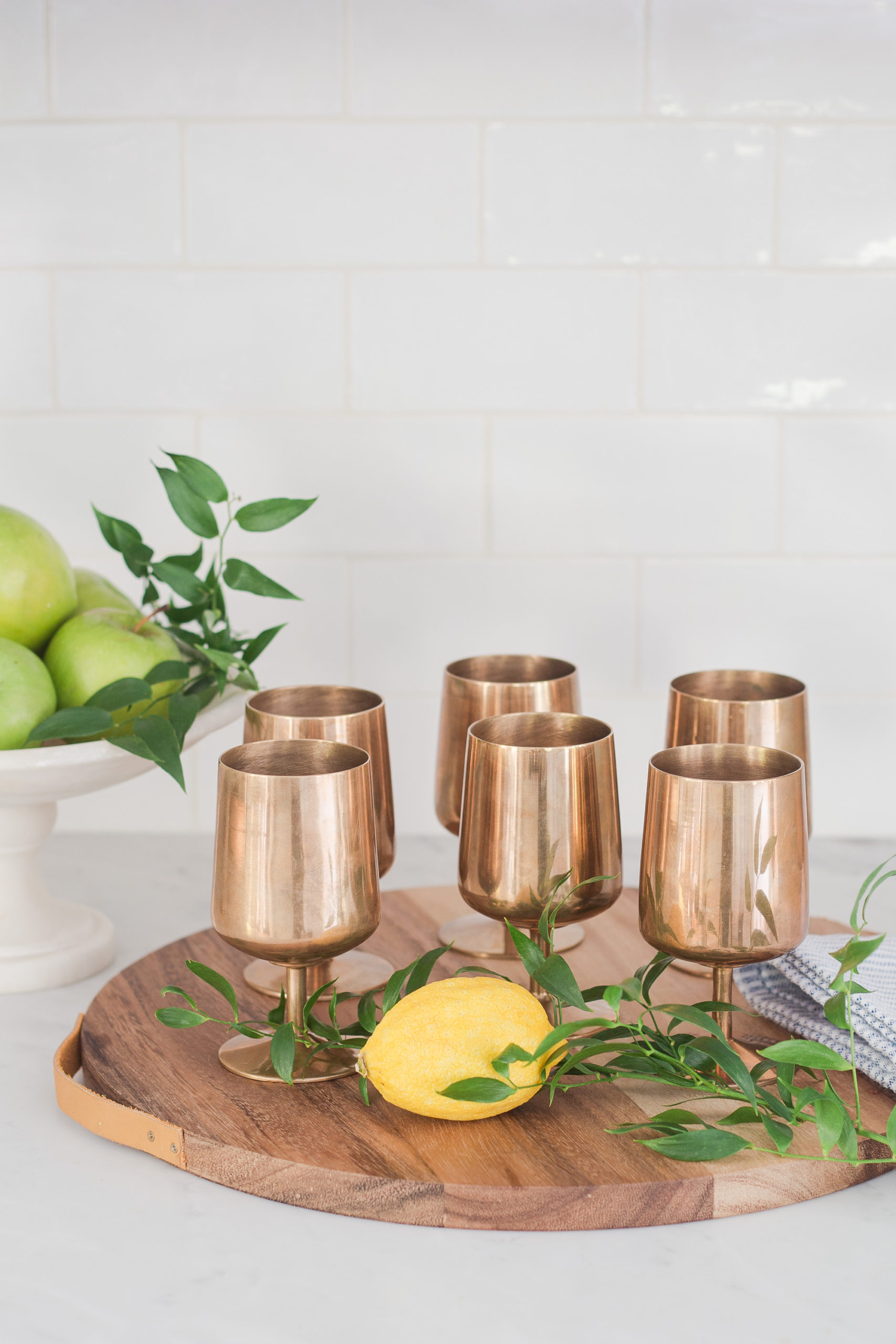 round wood tray with 6 copper goblets, lemon and greenery