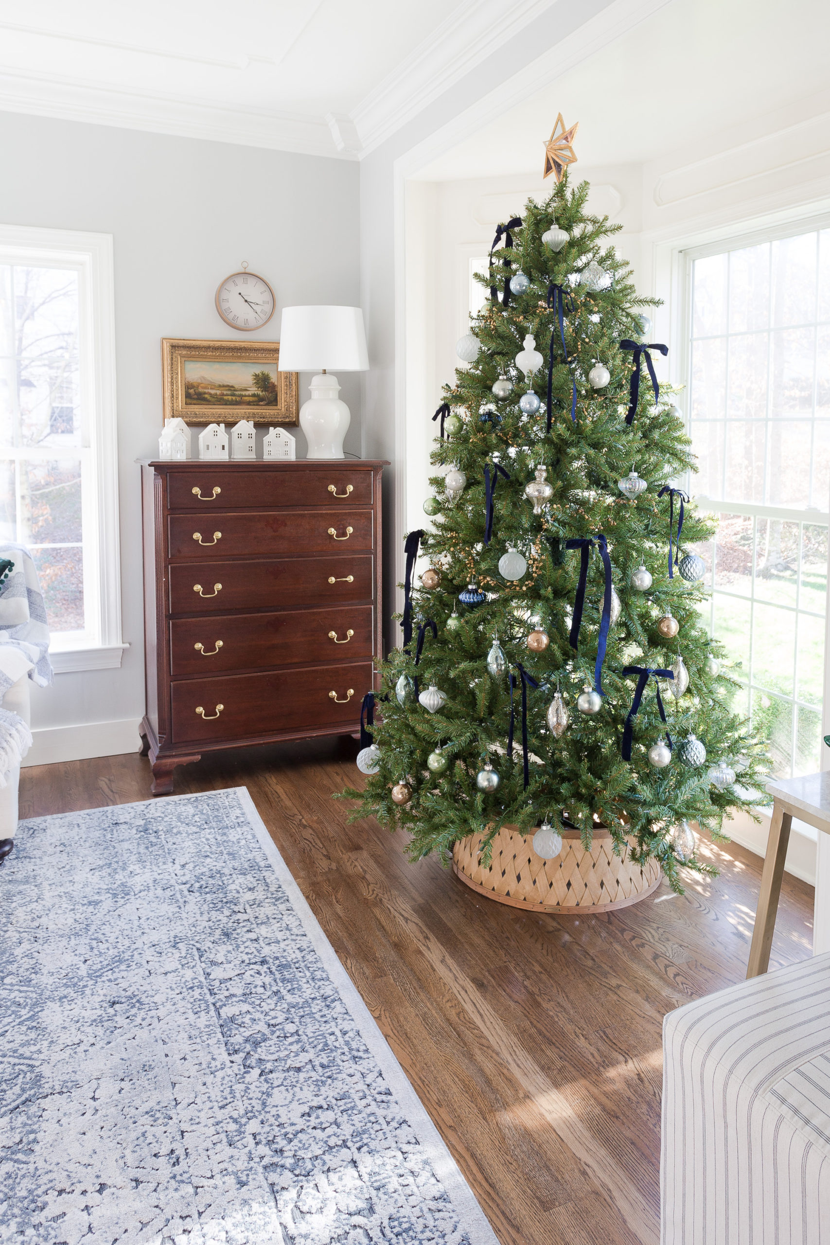 Christmas tree in living room with blue bows, ornaments and Christmas tree collar
