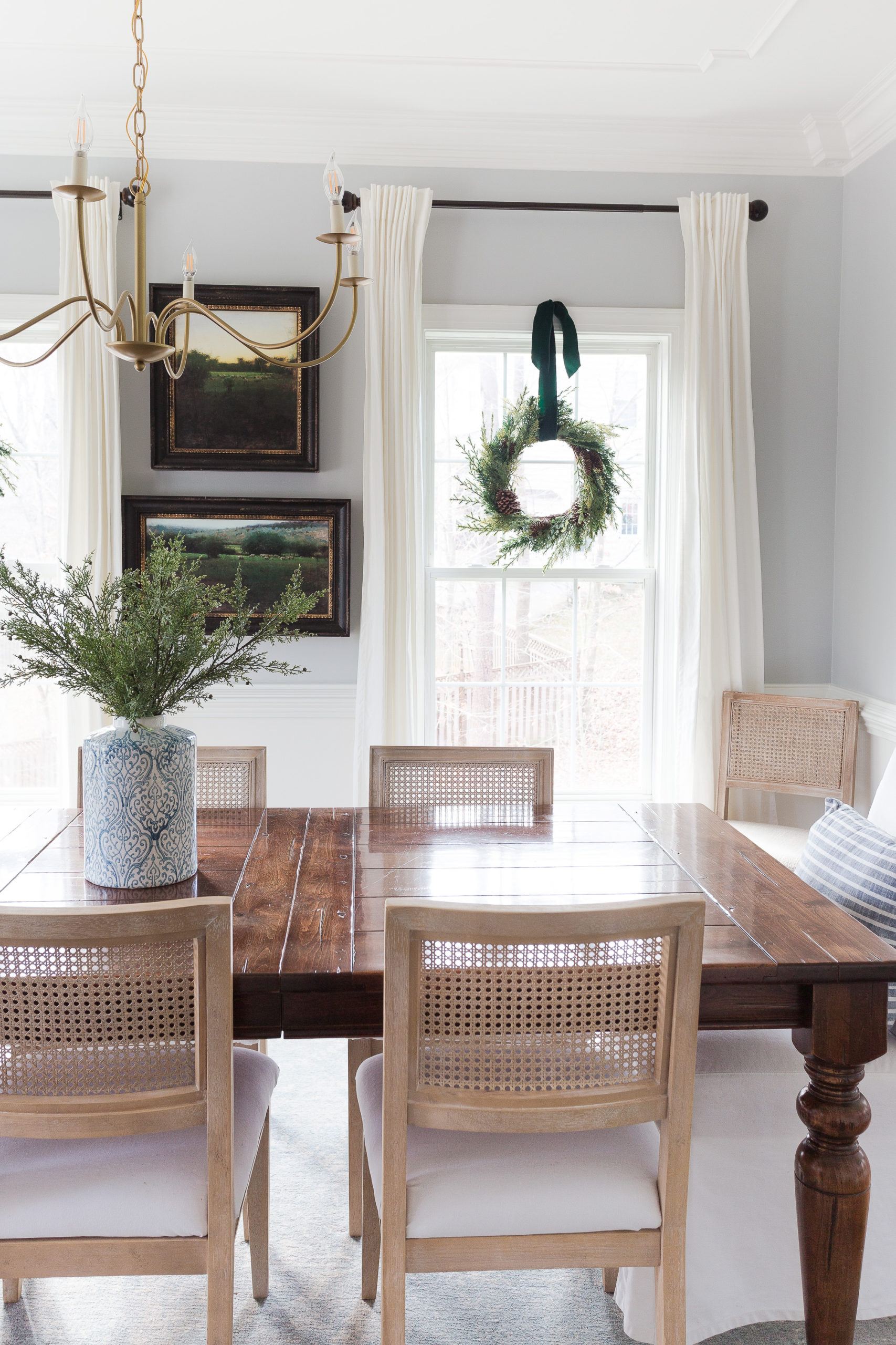 dining room with wreaths hanging in window with table and cane chairs
