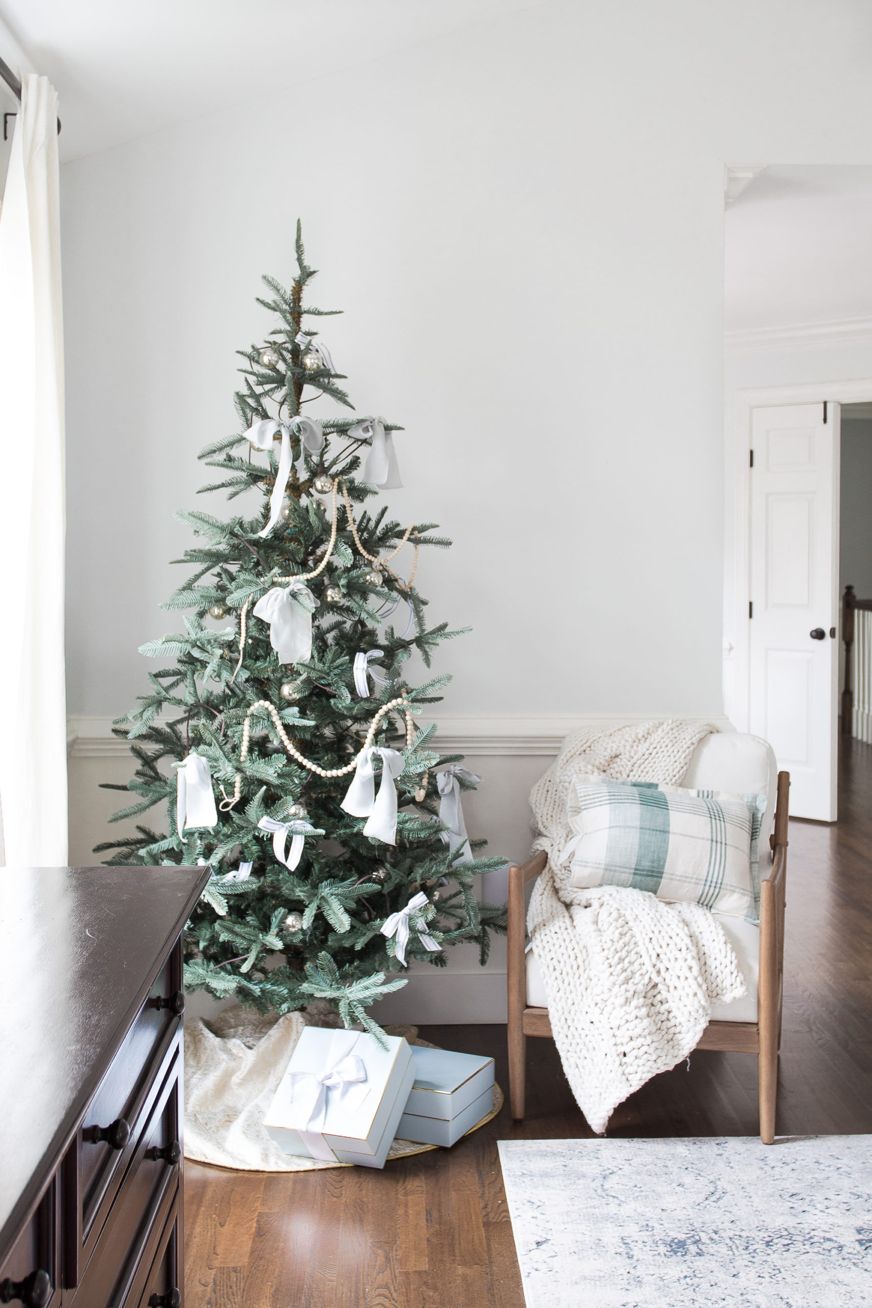 Christmas tree in bedroom with chair next to tree and presents underneath