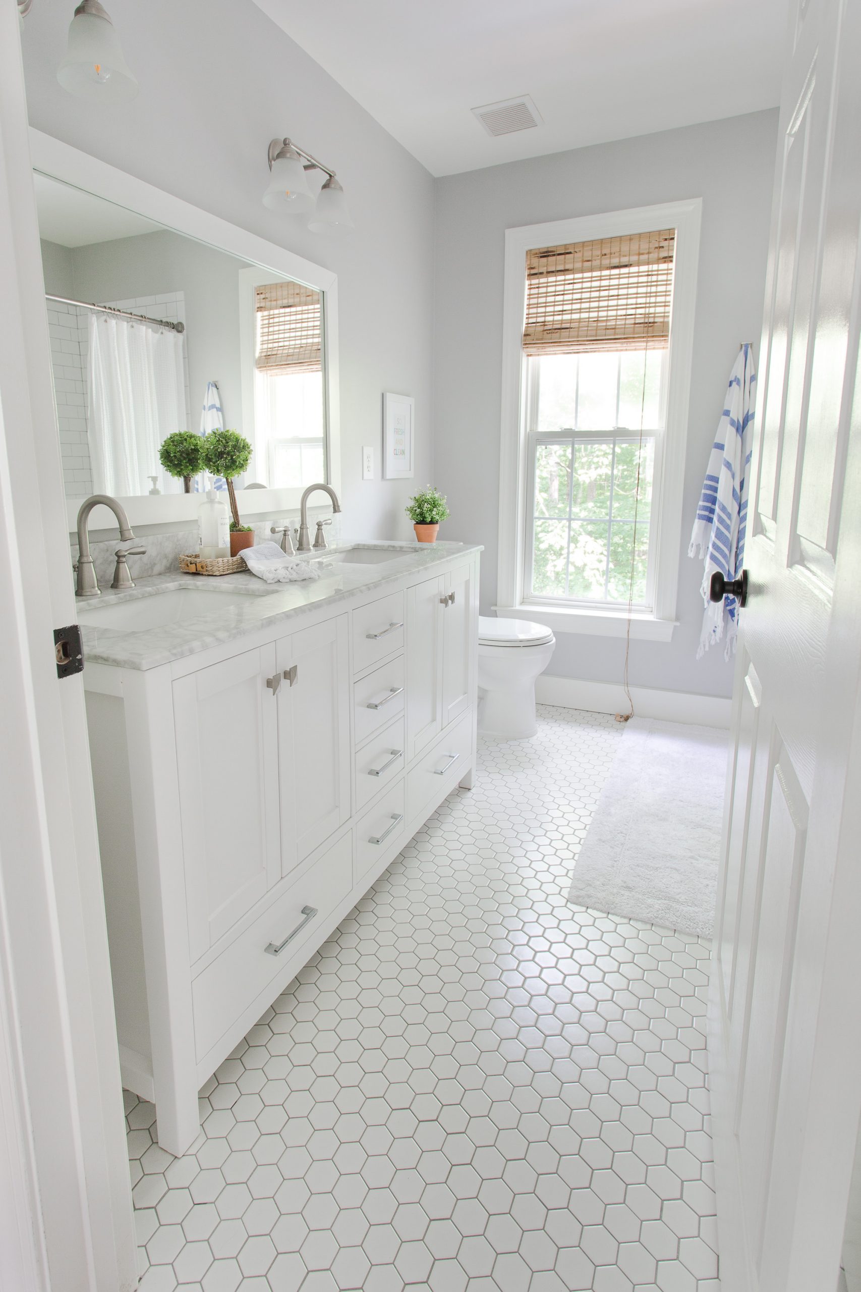 white bathroom with two sinks, hexagon tile floor and window
