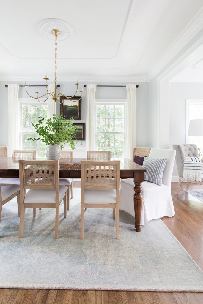 dining room with table, rug, cane chairs with a brass chandelier