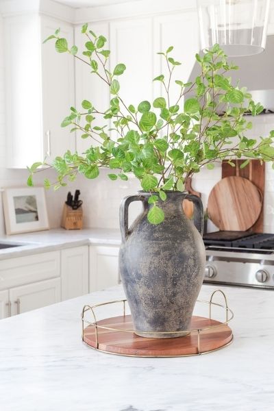 black weather pot with greenery sitting on kitchen marble countertop. 