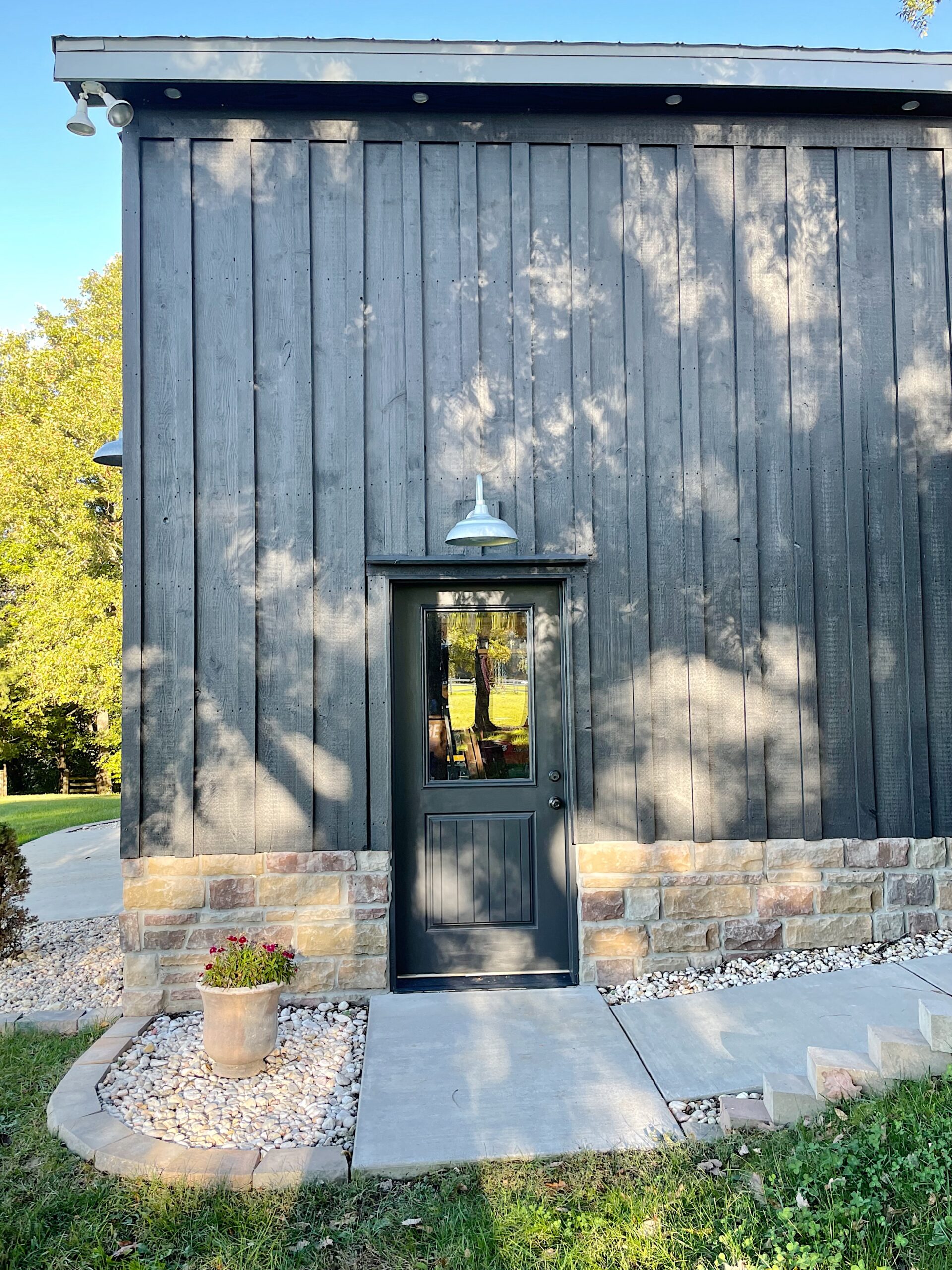 Black barn with door, silver barn light hanging above with stone foundation