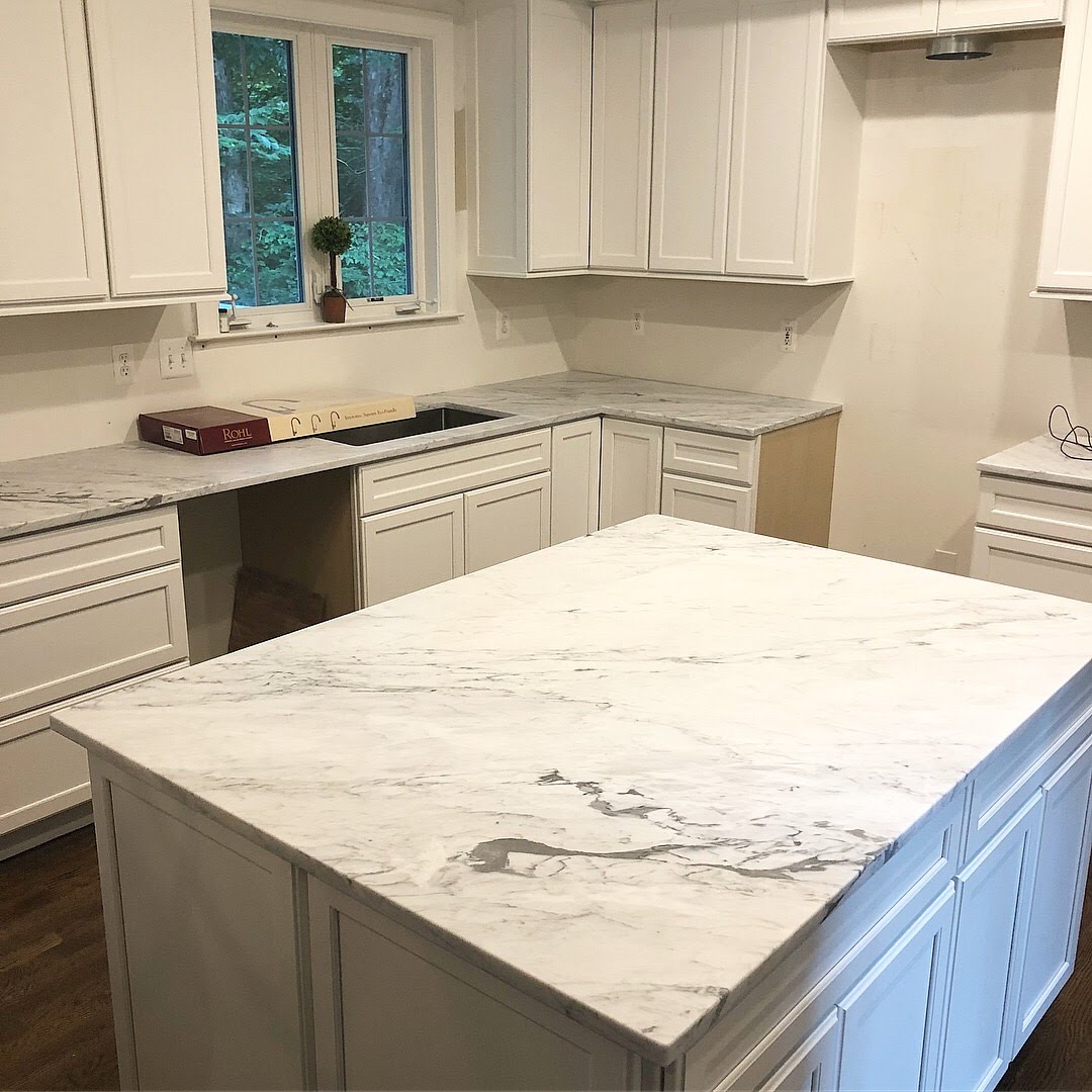 construction of white kitchen with marble countertops installed. 