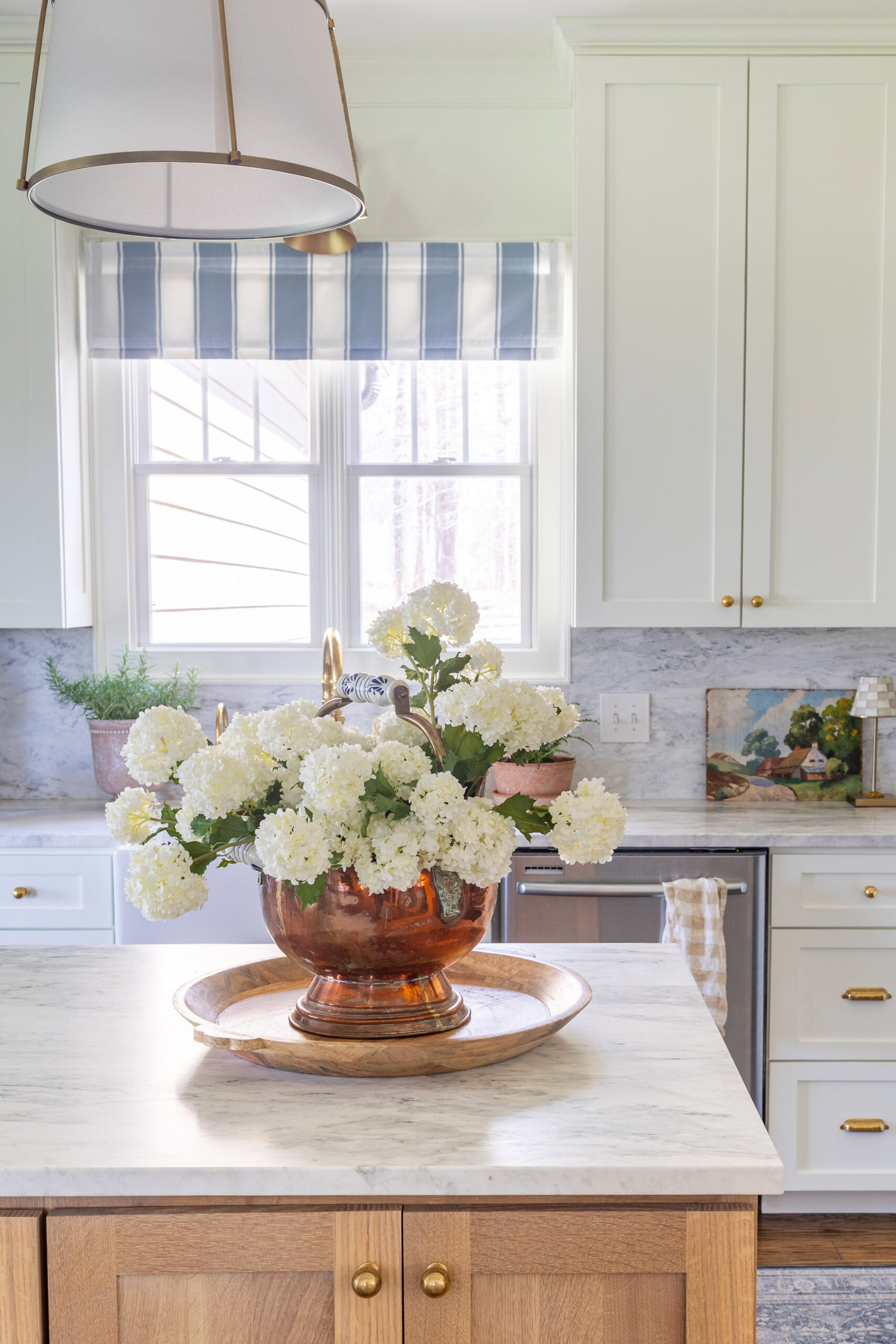 brass pot with white flowers on marble countertop in kitchen