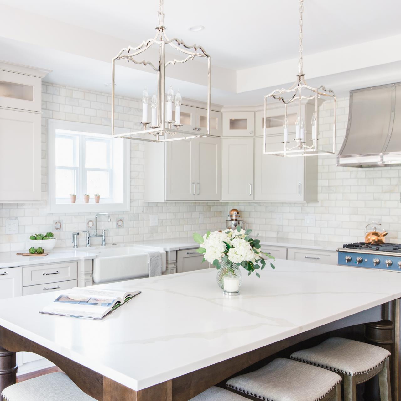 white kitchen with quartz countertop, marble tile backsplash with a blue gas range