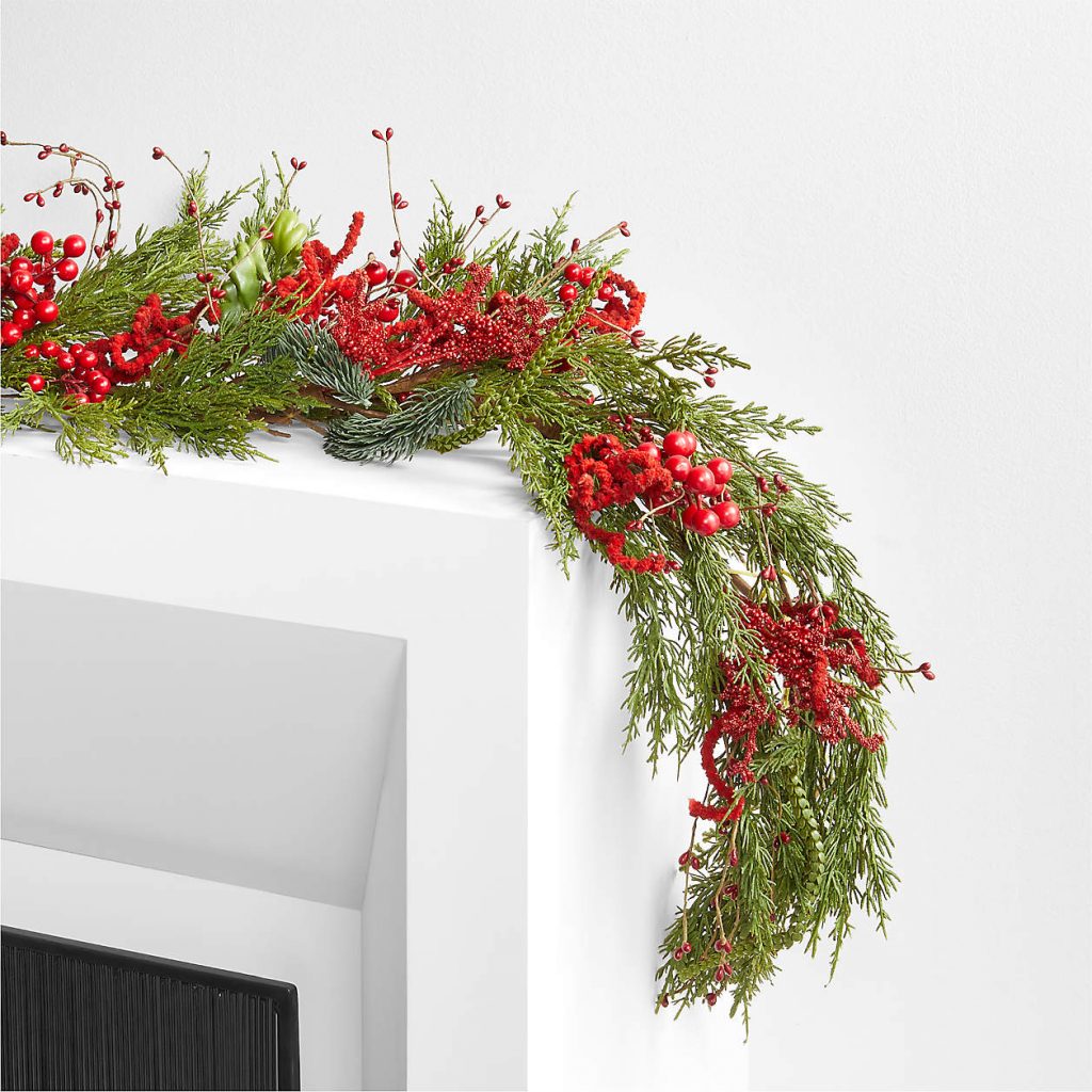 red berry and green garland draped on white fireplace