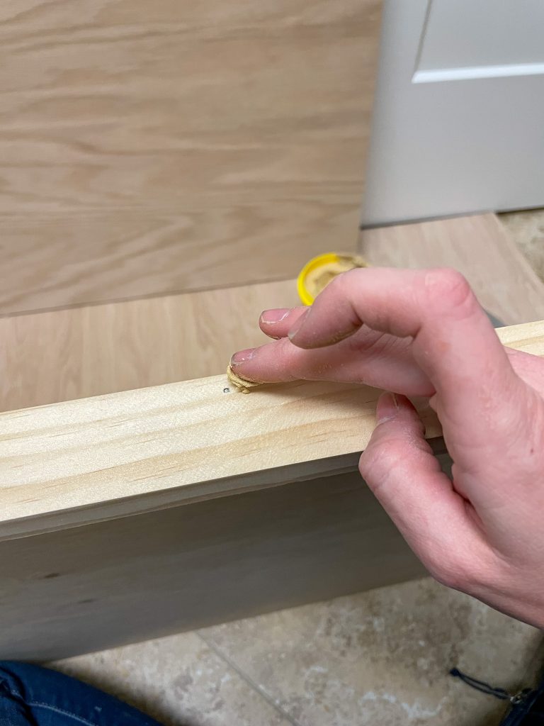 finger putting on wood filler on nail wholes