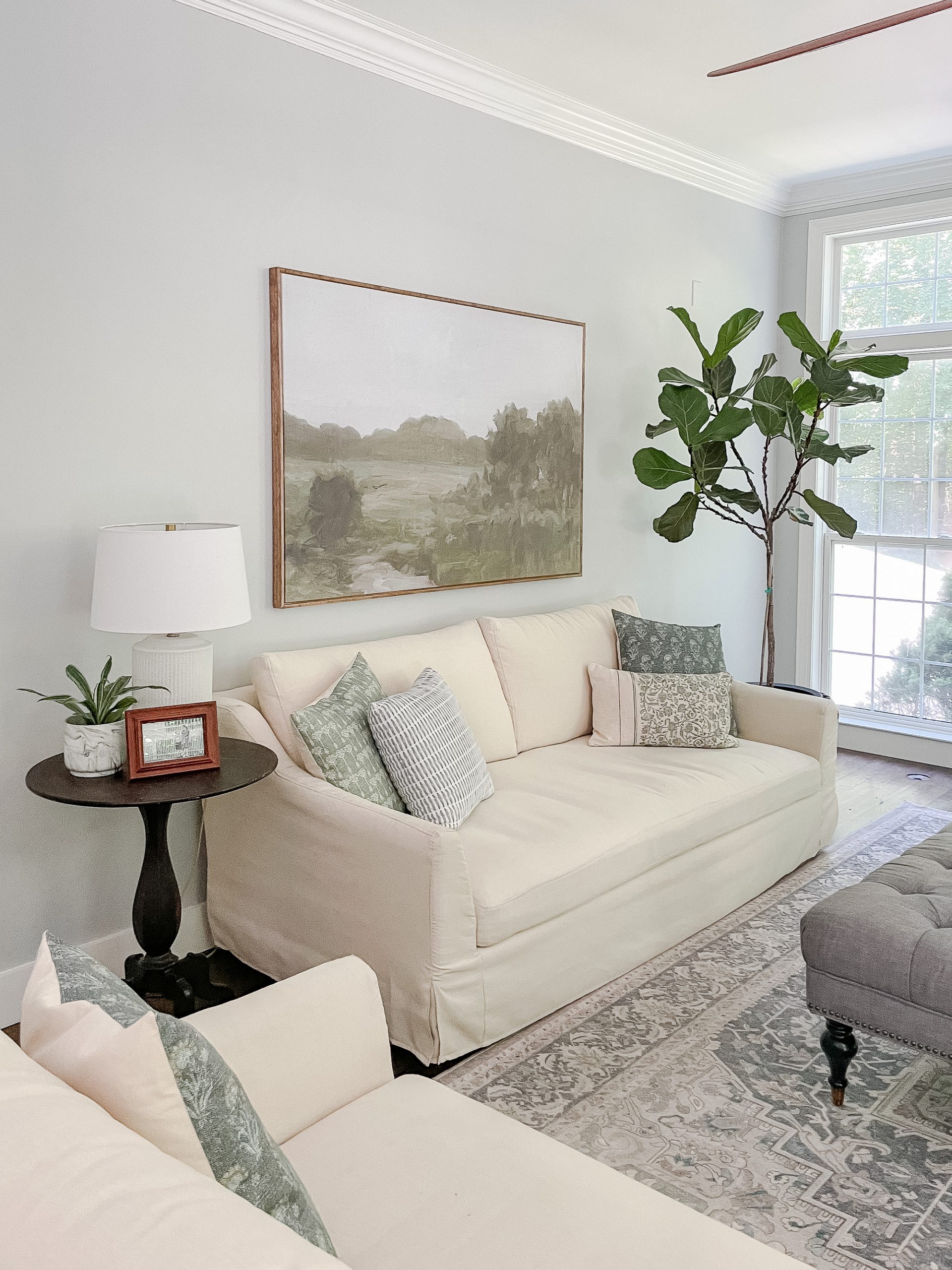 decorate a large wall in Family room with large art above sofa, fiddle leaf tree next to a window. 