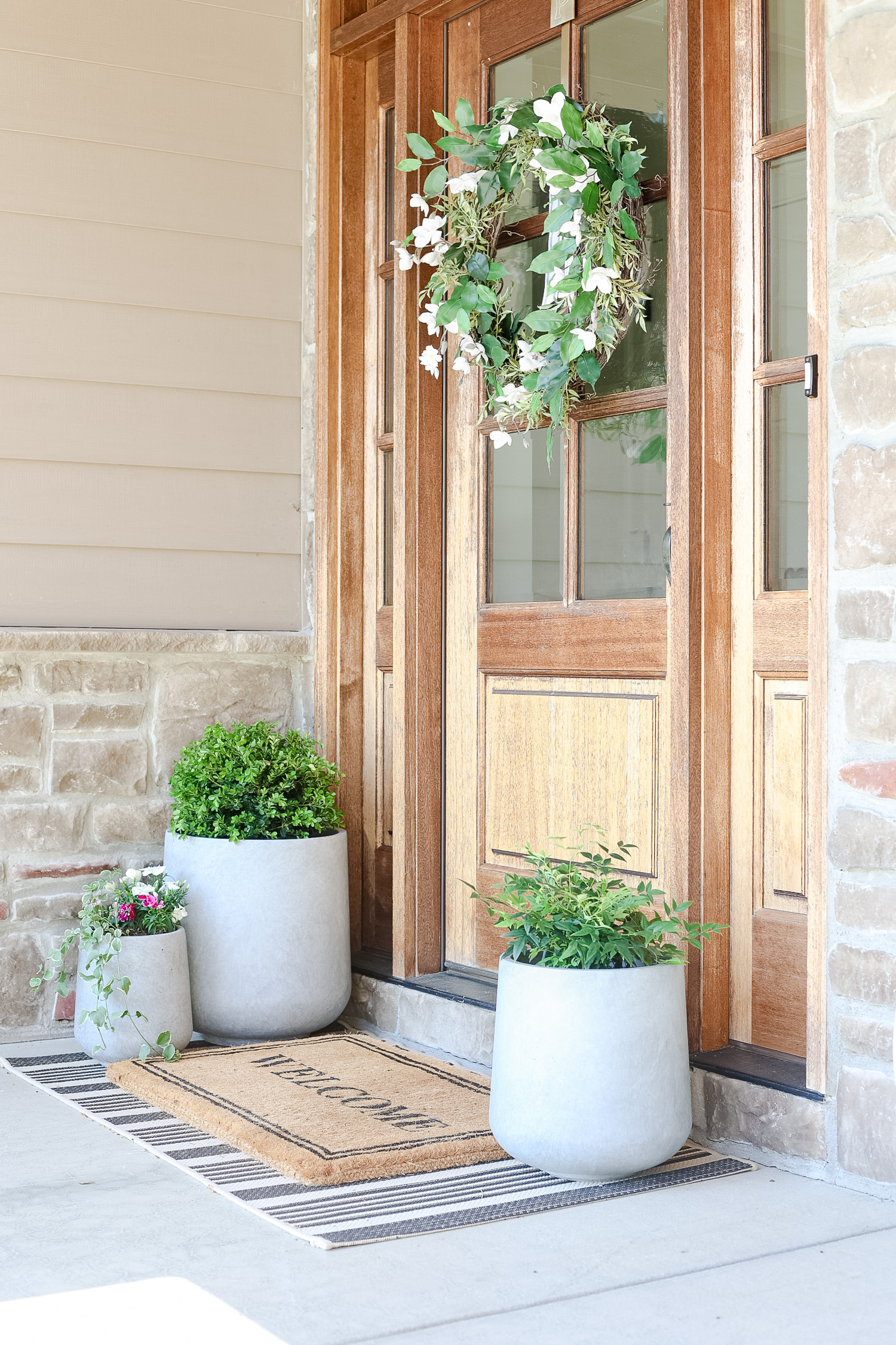 front glass door with wreath and three outdoor planters with flowers