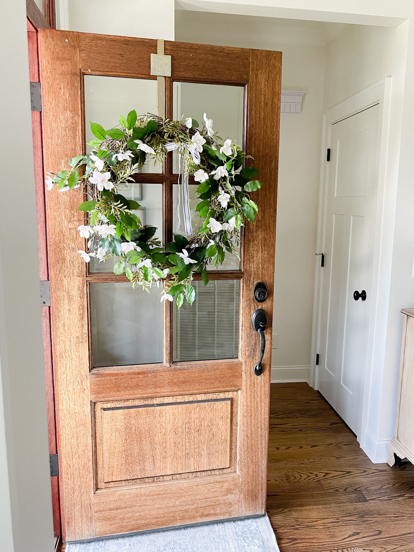 Wood front door with glass panes and green and floral wreath on door