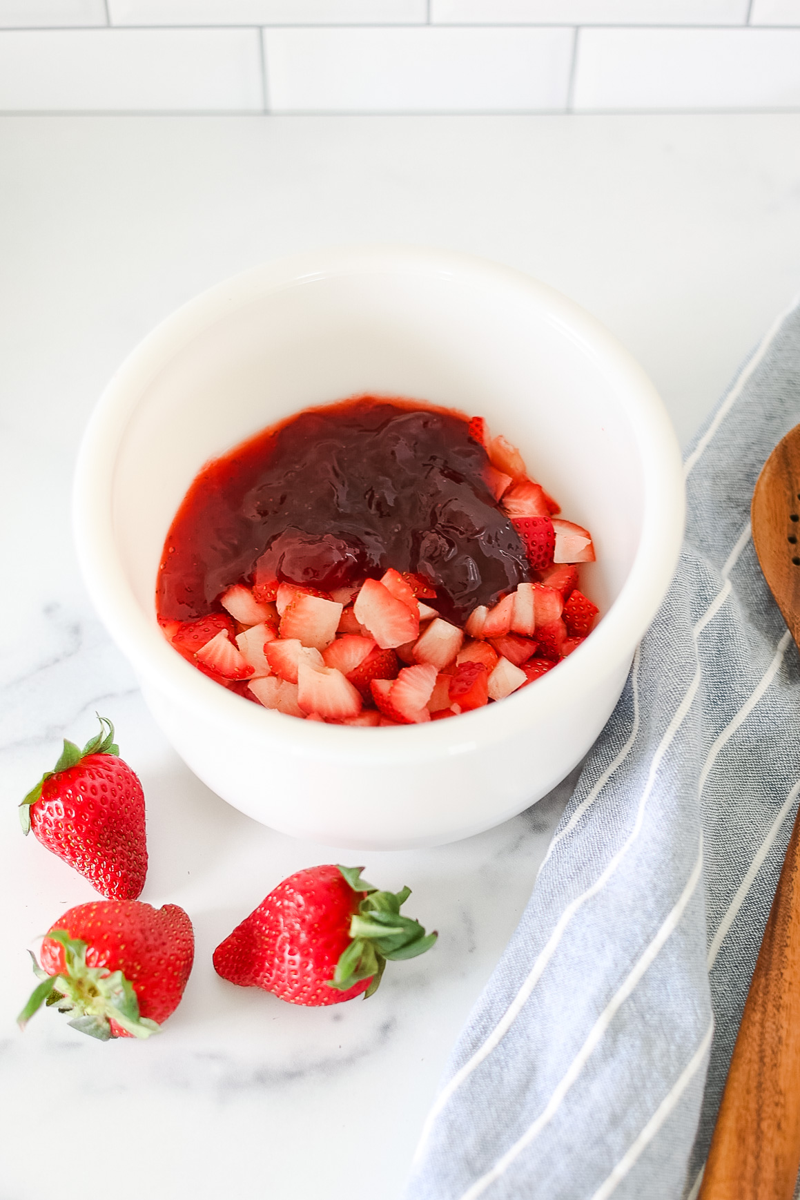 bowl of diced strawberries and jam with wooden spoon