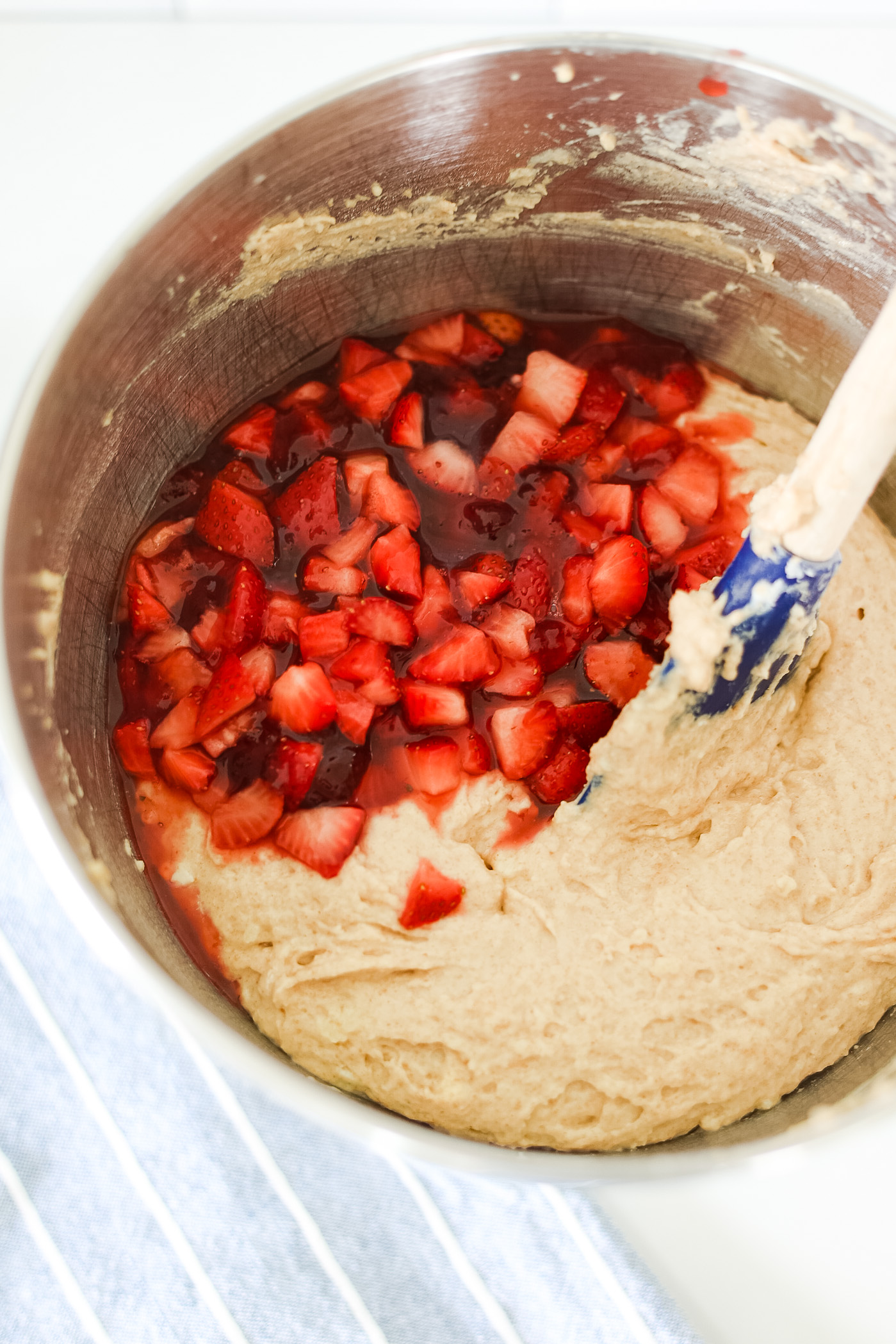 mixing bowl with batter and diced strawberries and jam with spatula
