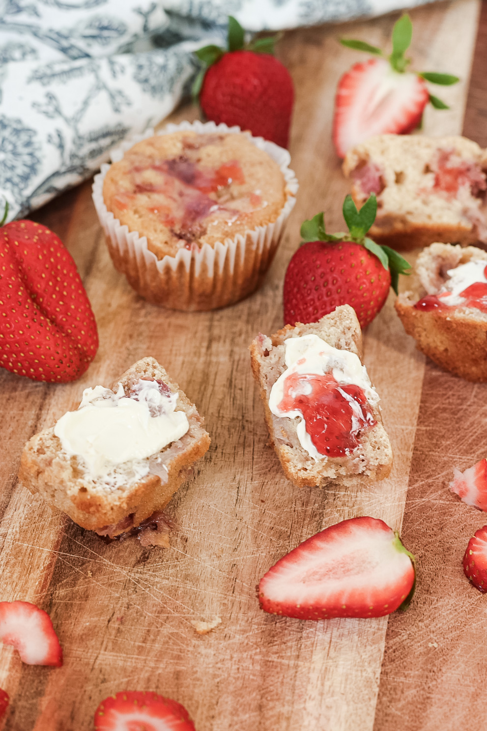 Strawberries and strawberry muffins on a wooden cutting board. 