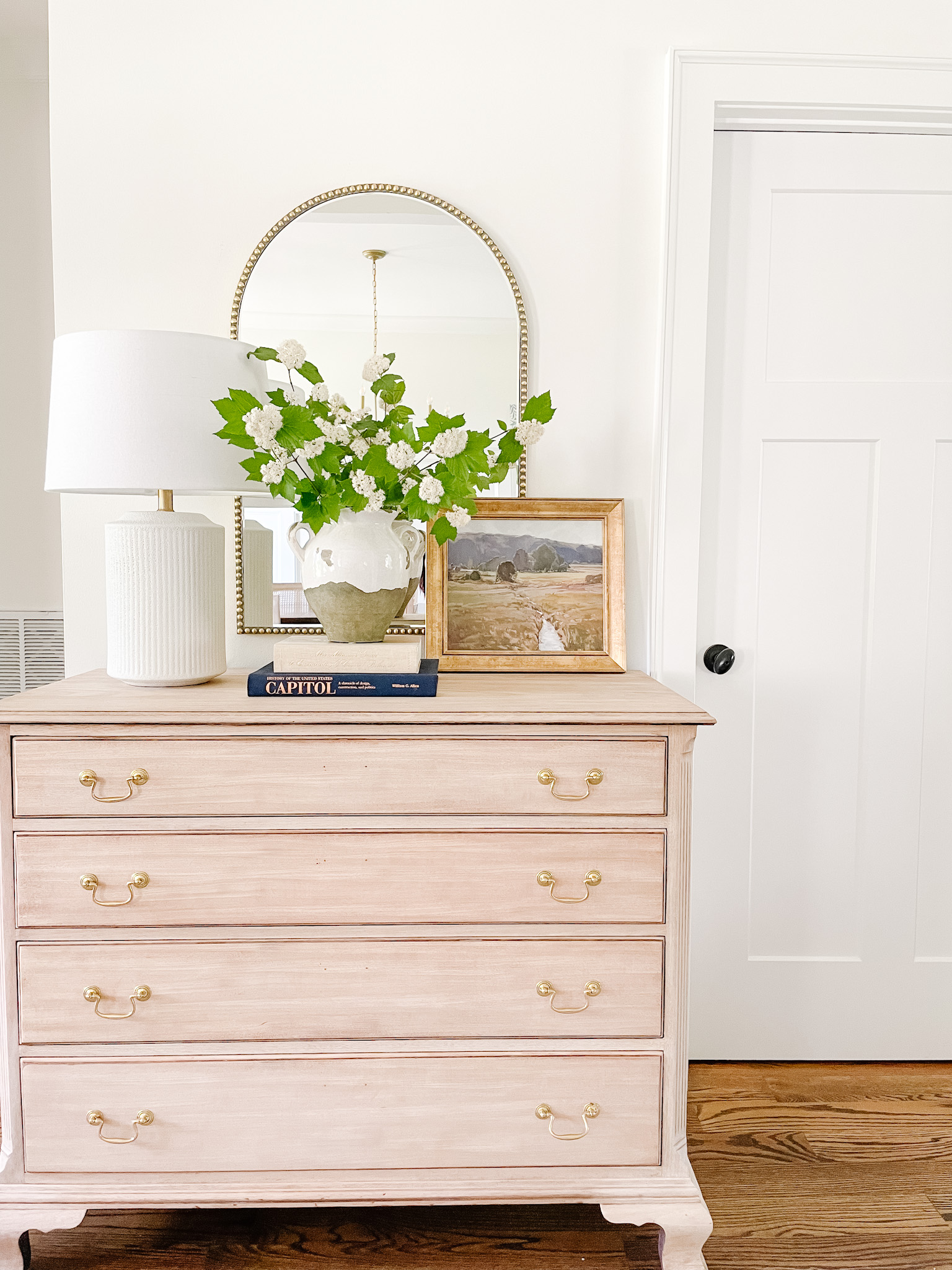 dresser in foyer with lamp and vase of greenery