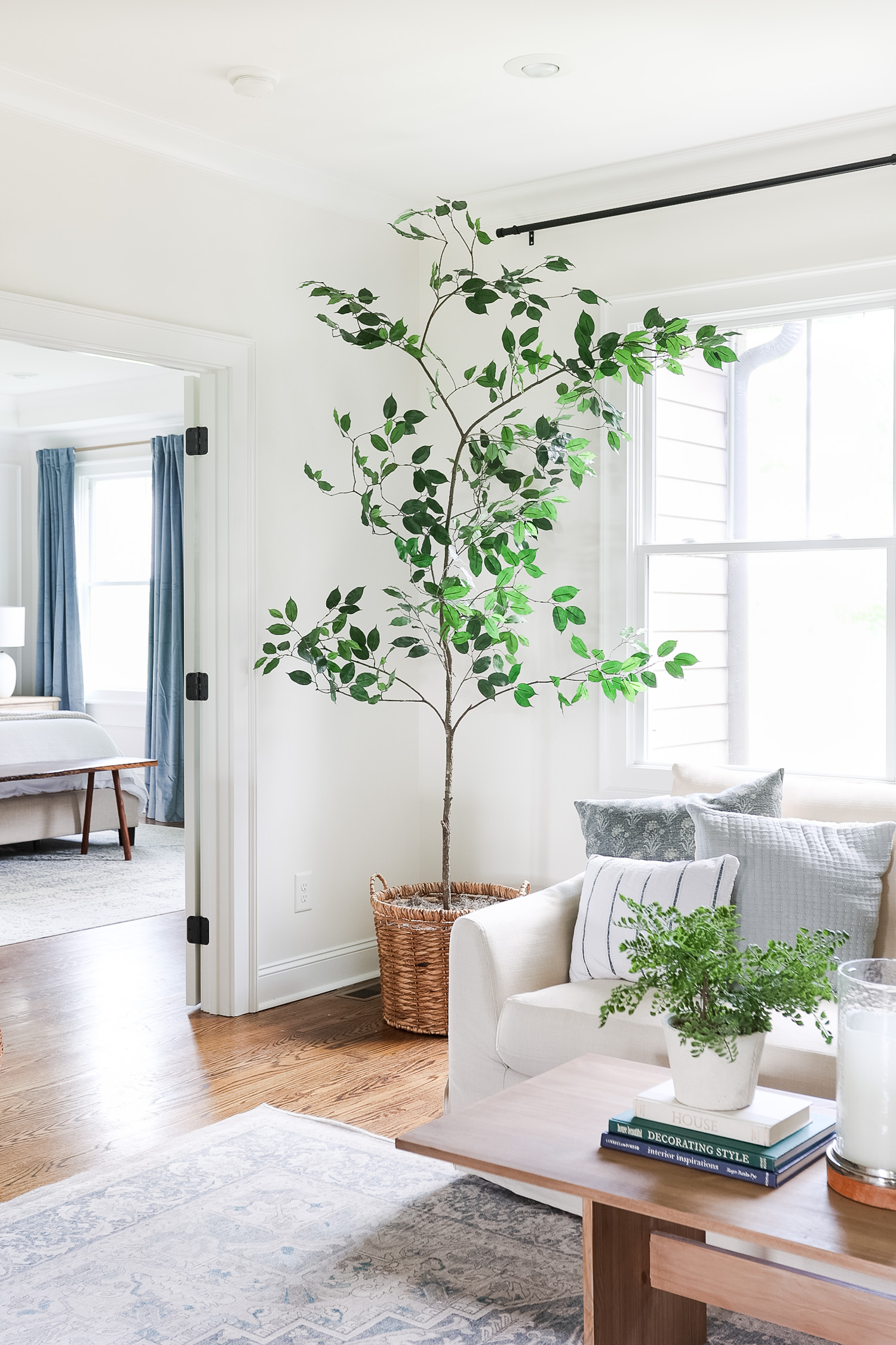 fake tree in living room sitting in basket next to window