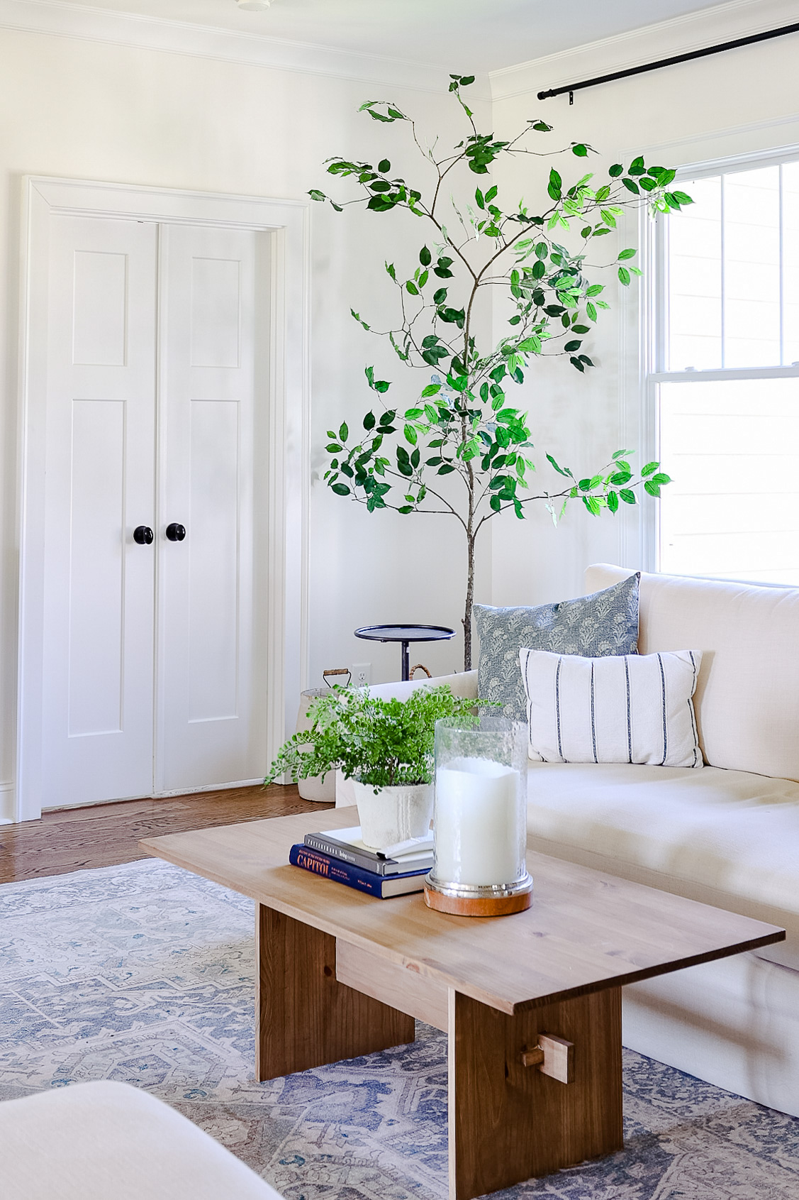 fake tree in living room sitting in basket next to window