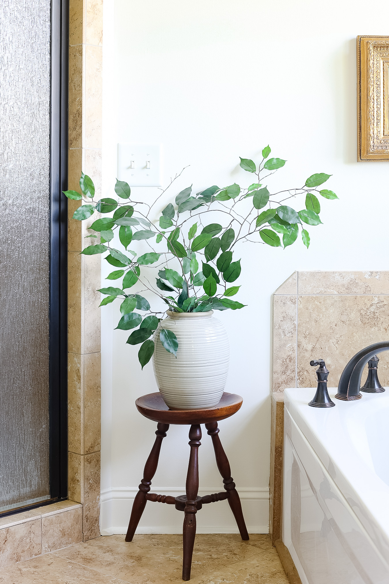 bathtub with towel and artwork with vase of greenery