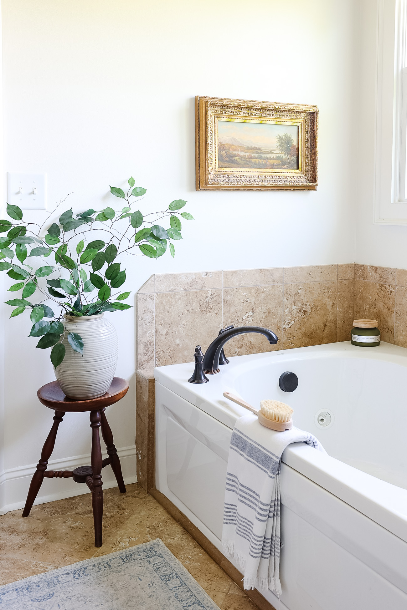 bathtub with towel and artwork with vase of greenery