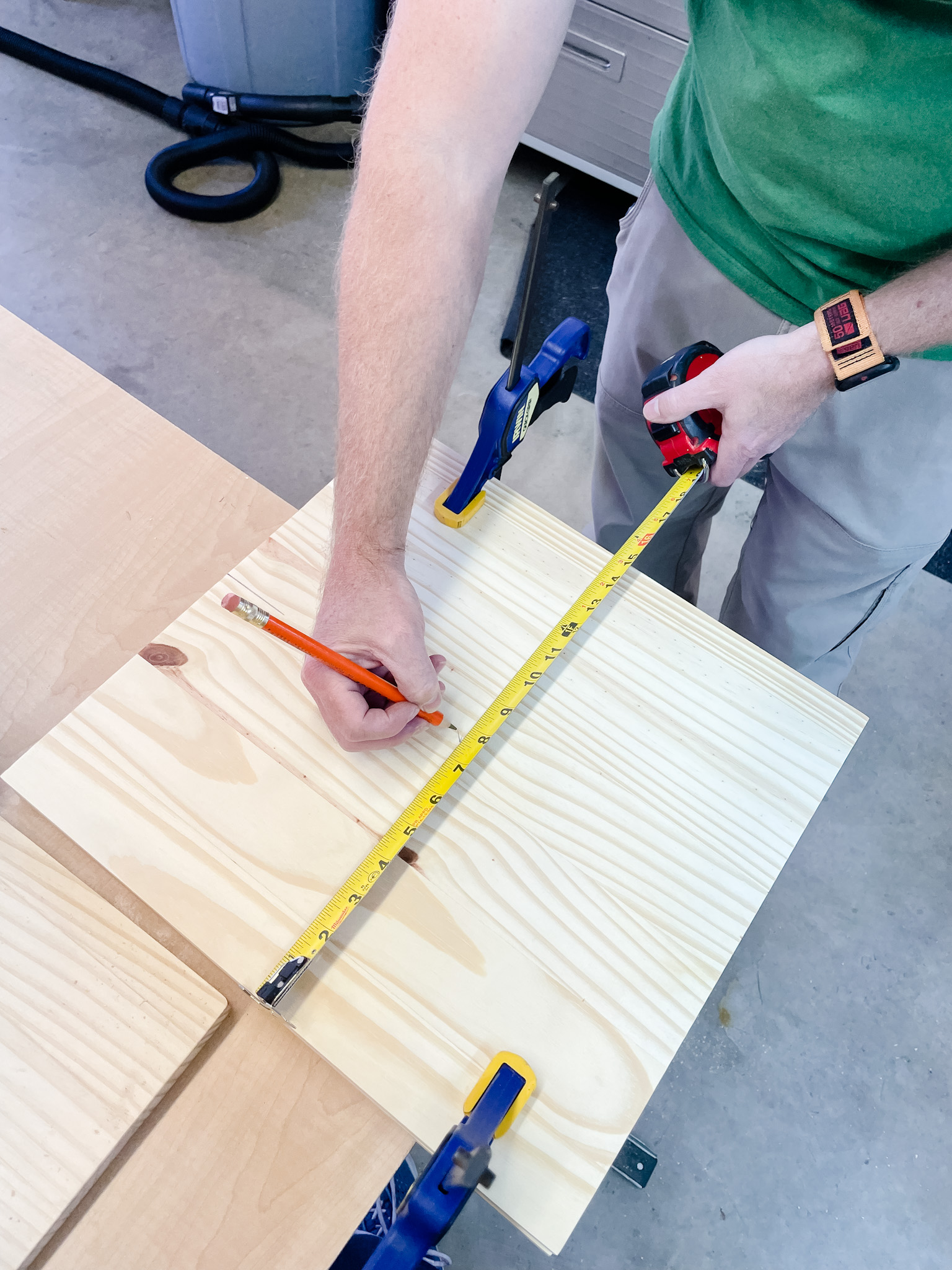 person measuring on wood with tape measure