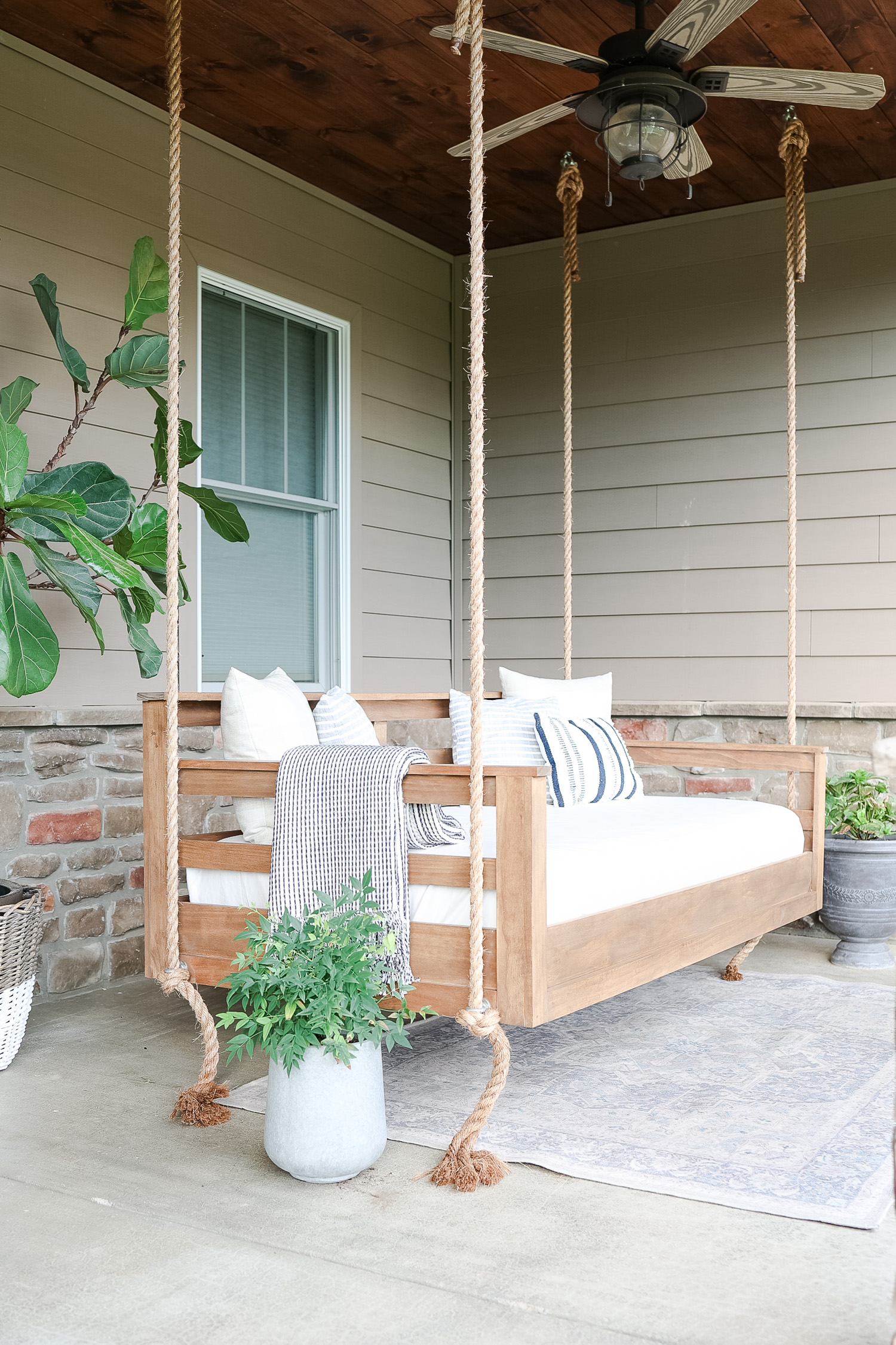 wood patio swing with blanket and pillows