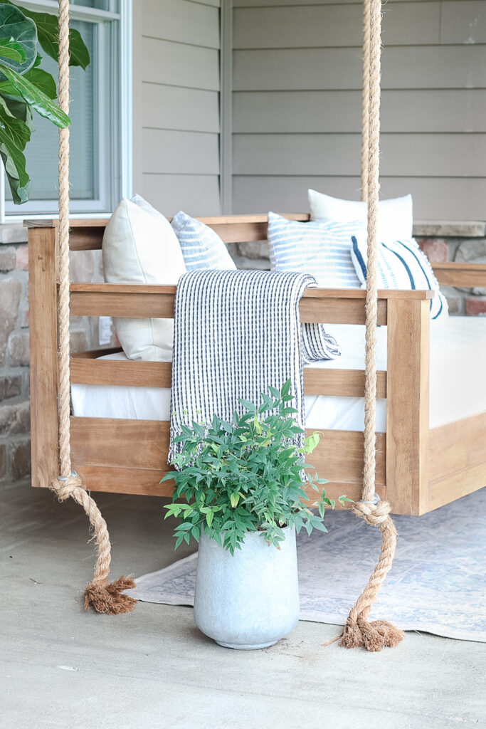 wood patio swing with blanket and pillows