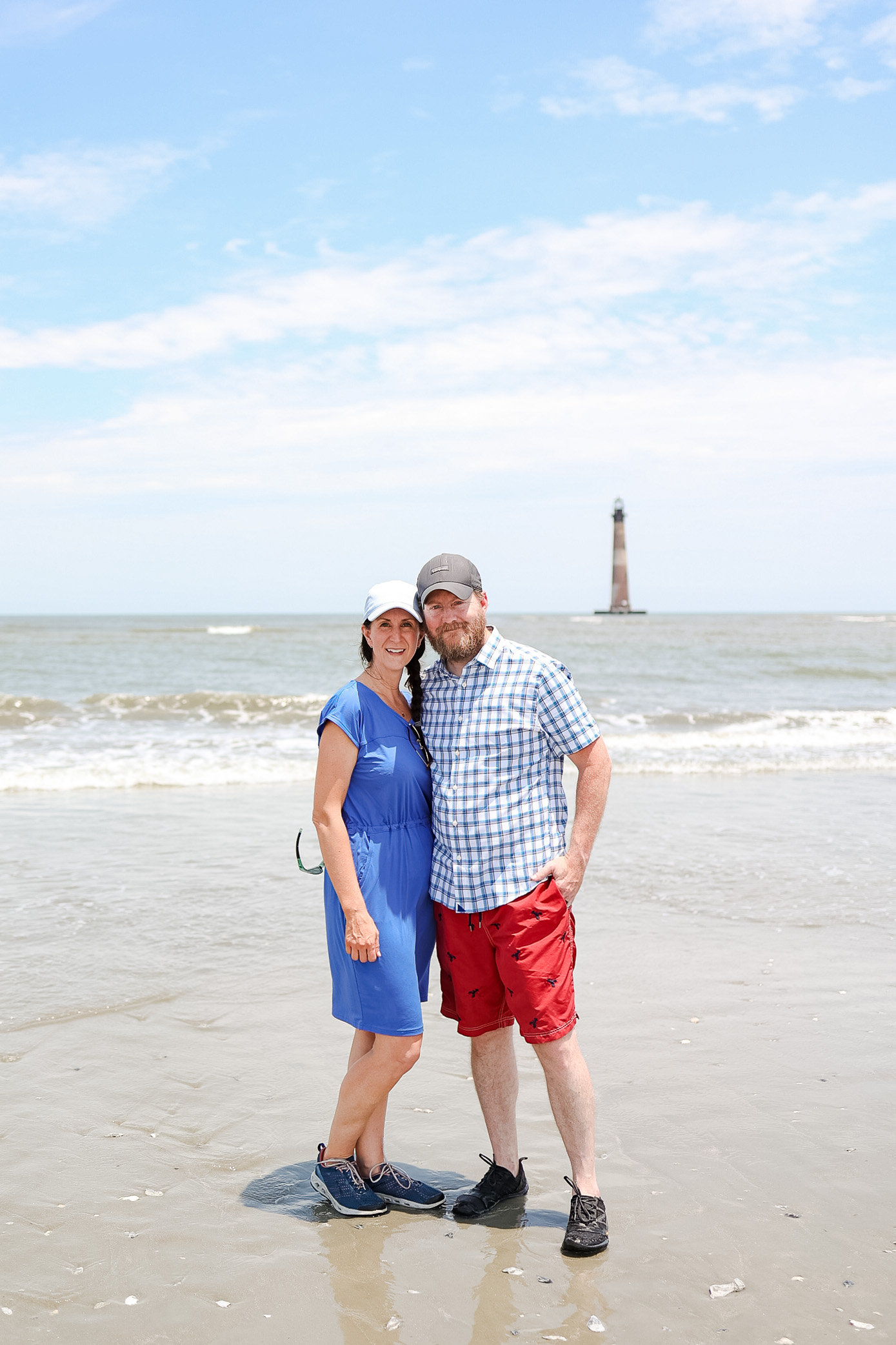 couple on beach with lighthouse behind them