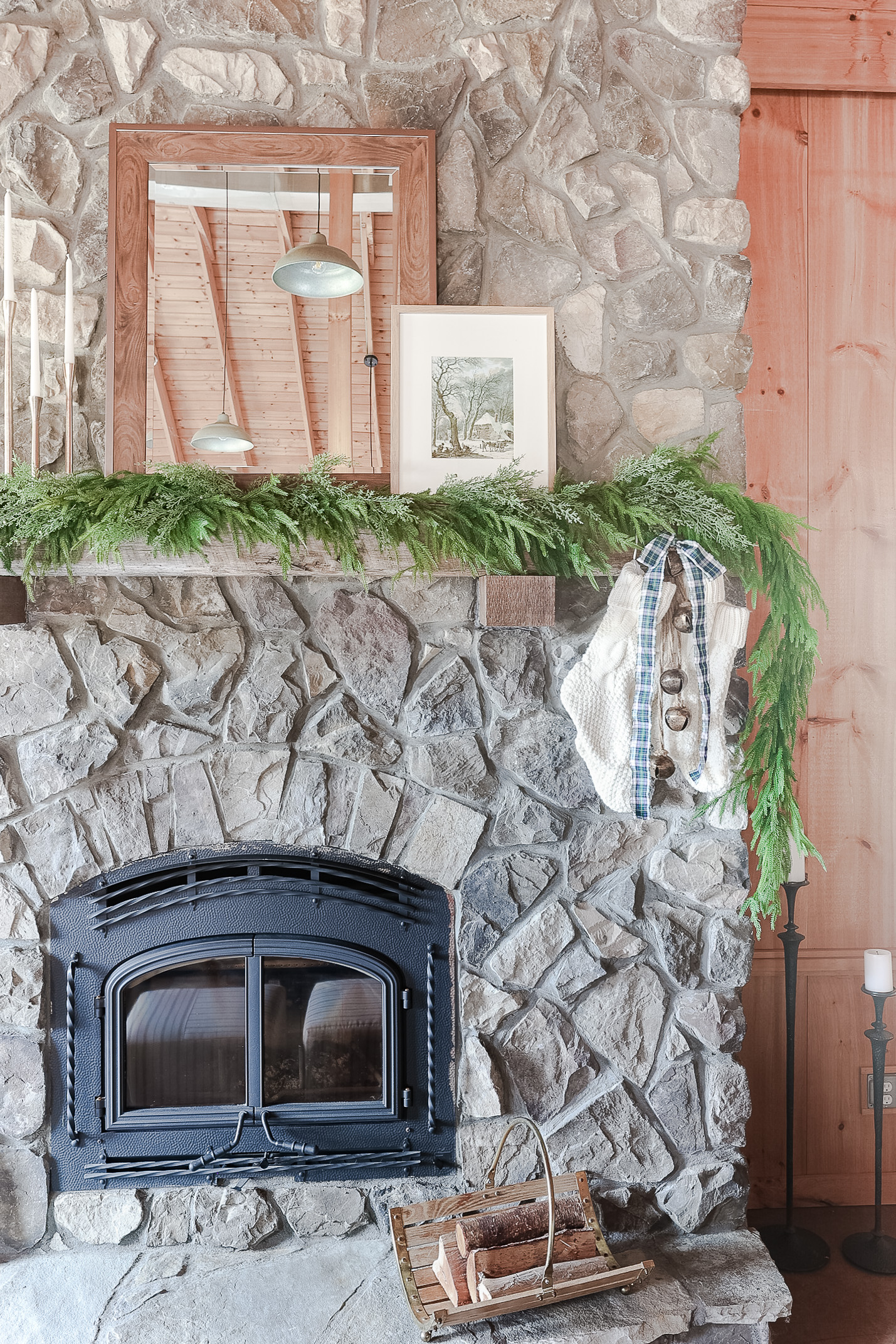stone fireplace with winter vintage art and mirror with christmas stockings