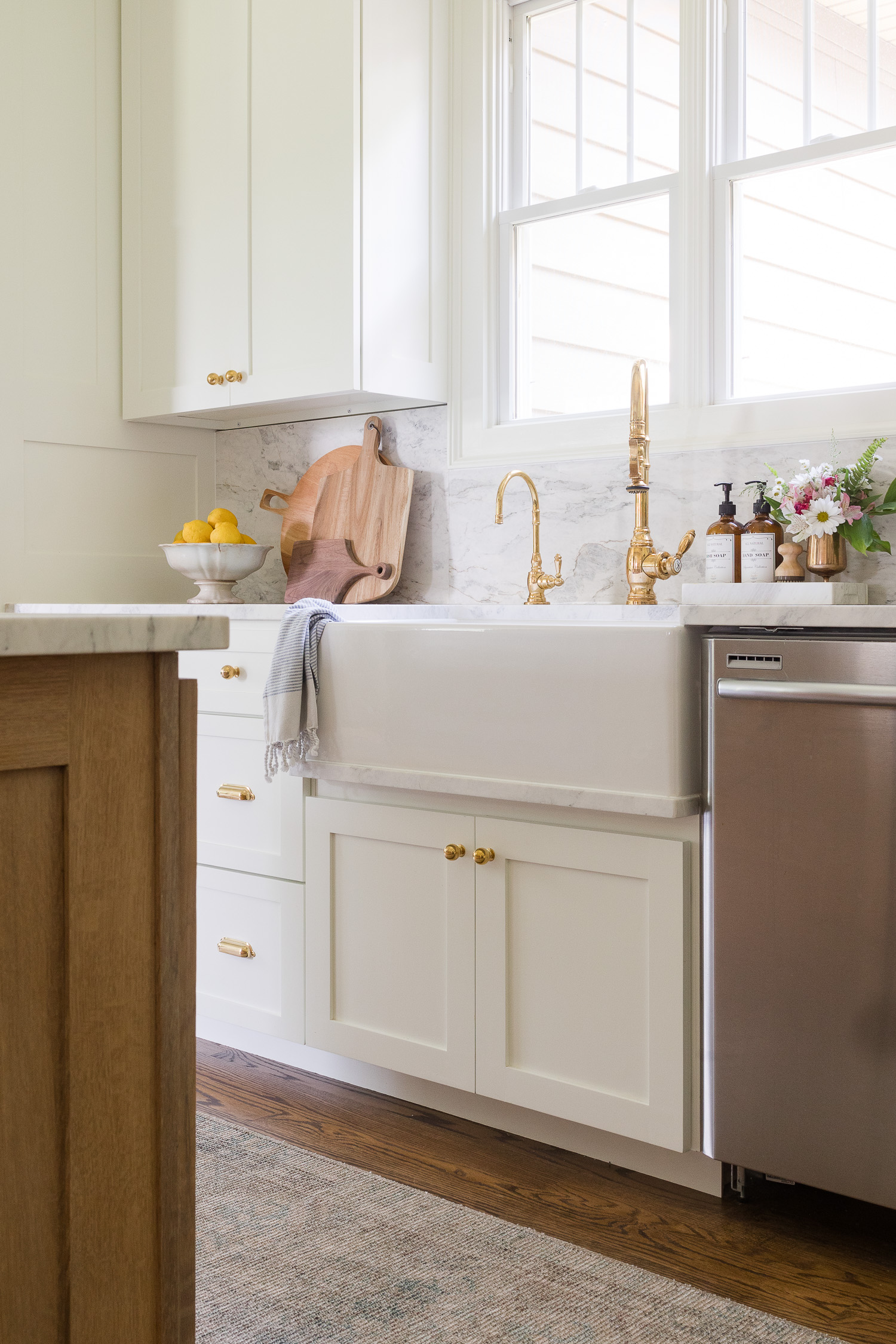 white kitchen farmhouse sink with white cabinets and brass faucet