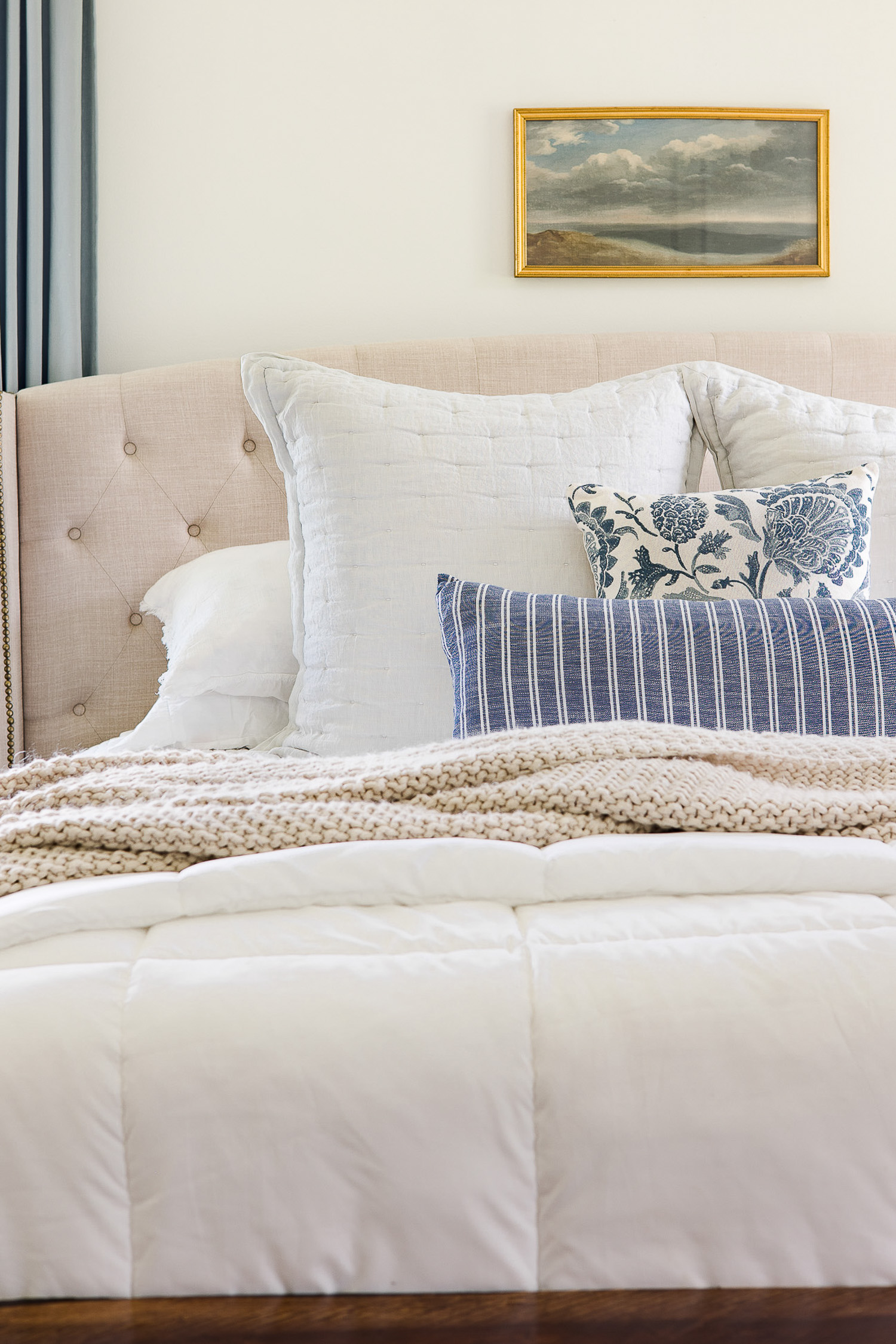 blue and white pillows on upholstered bed