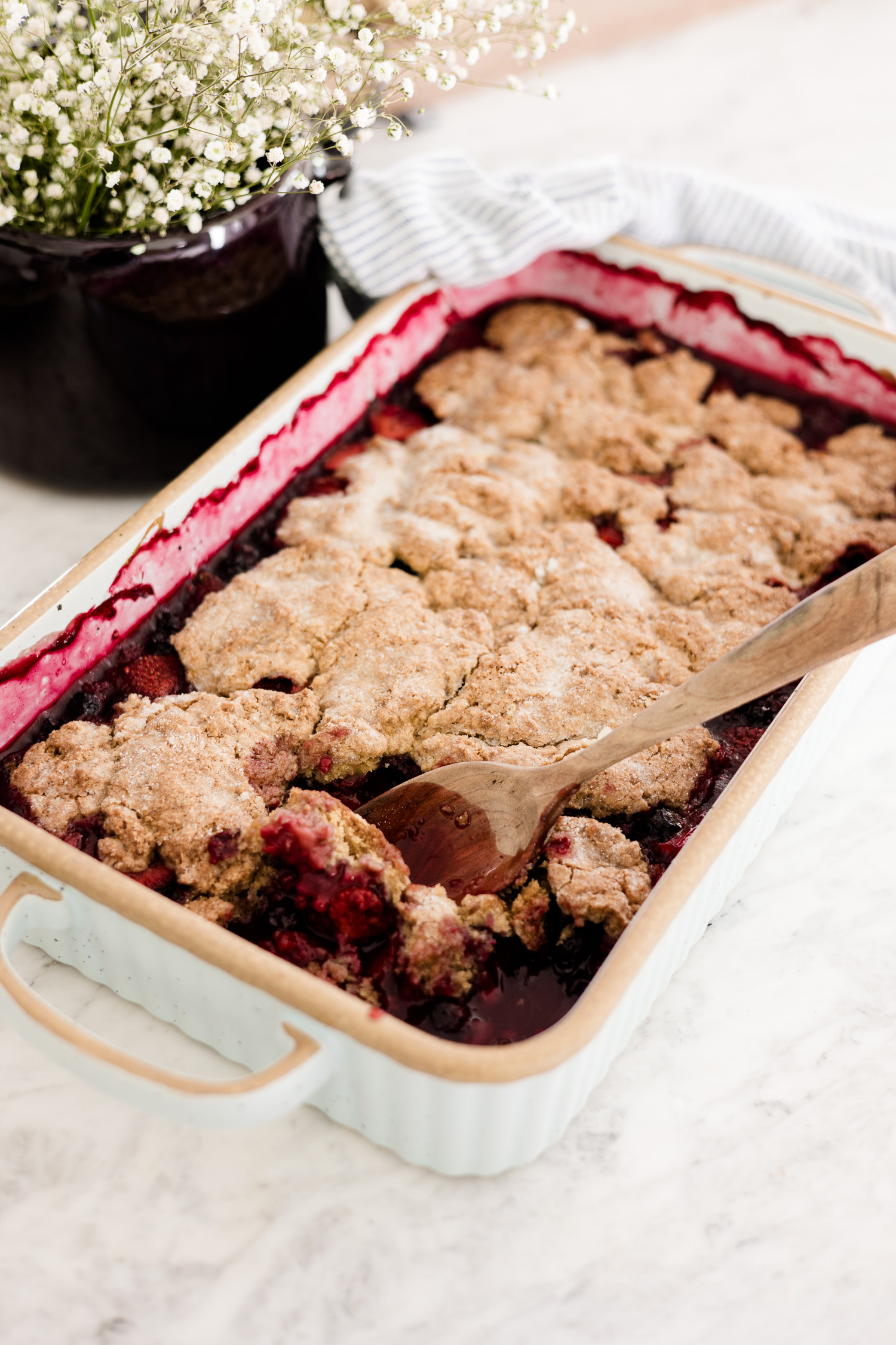 mixed Berry cobbler in casserole dish with wooden spoon