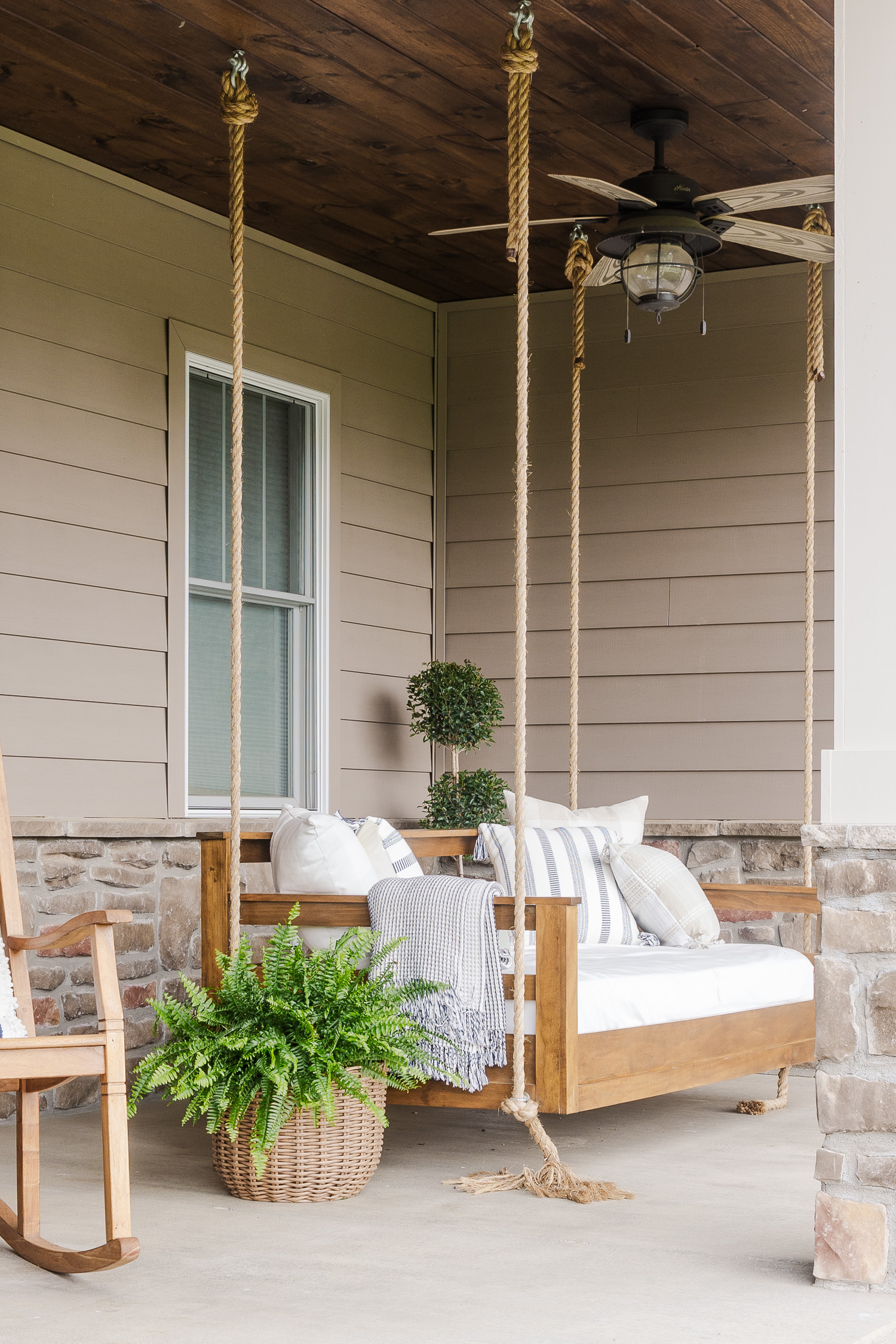 porch swing bed on patio with fern, pillows and blanket