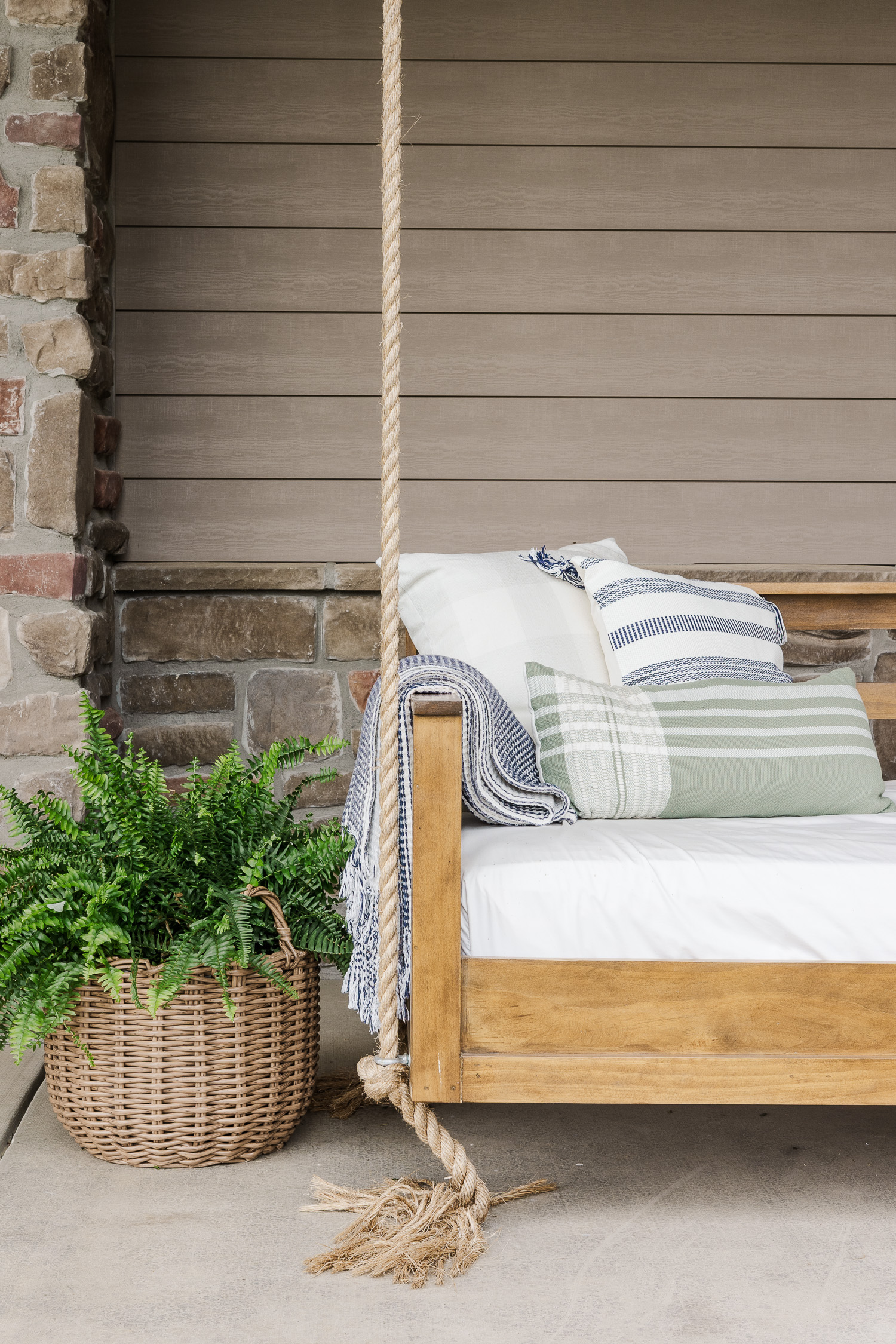 porch swing bed on patio with fern, pillows and blanket