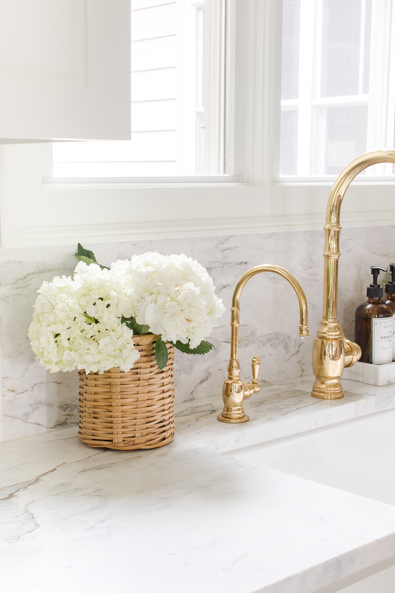 basket of white hydrangeas sitting on kitchen counter next to sink