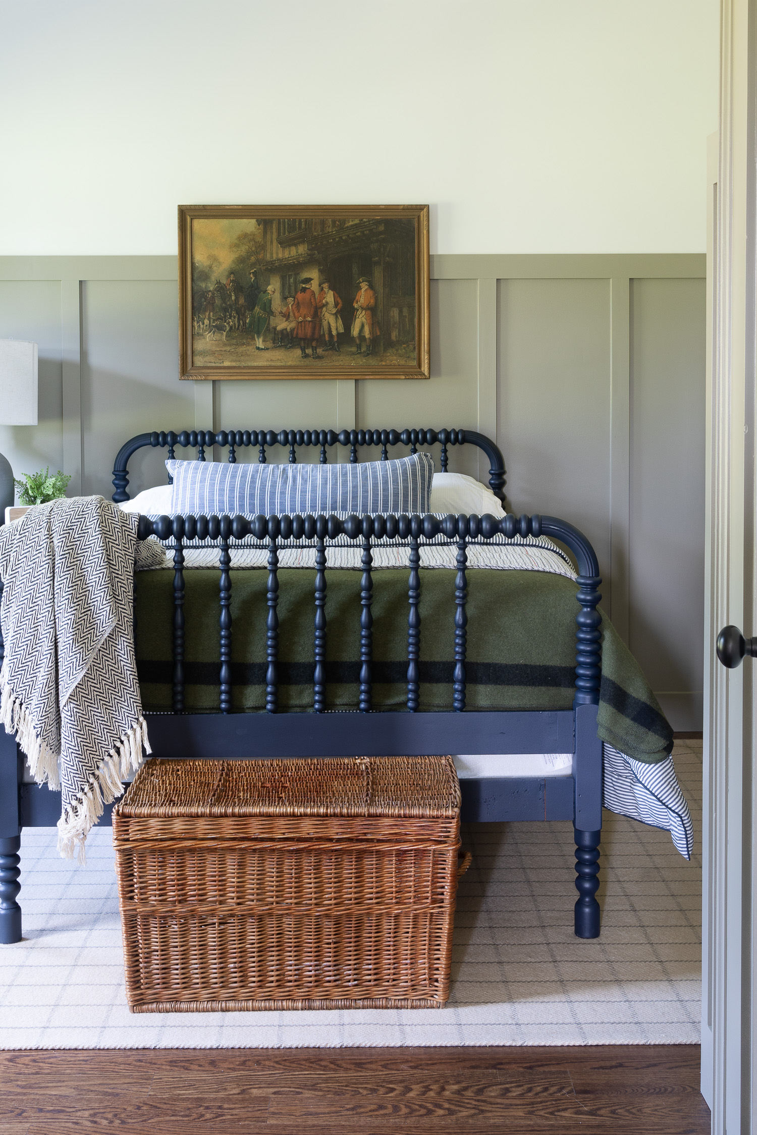 wicker basket at end of blue spindle bed in boy bedroom