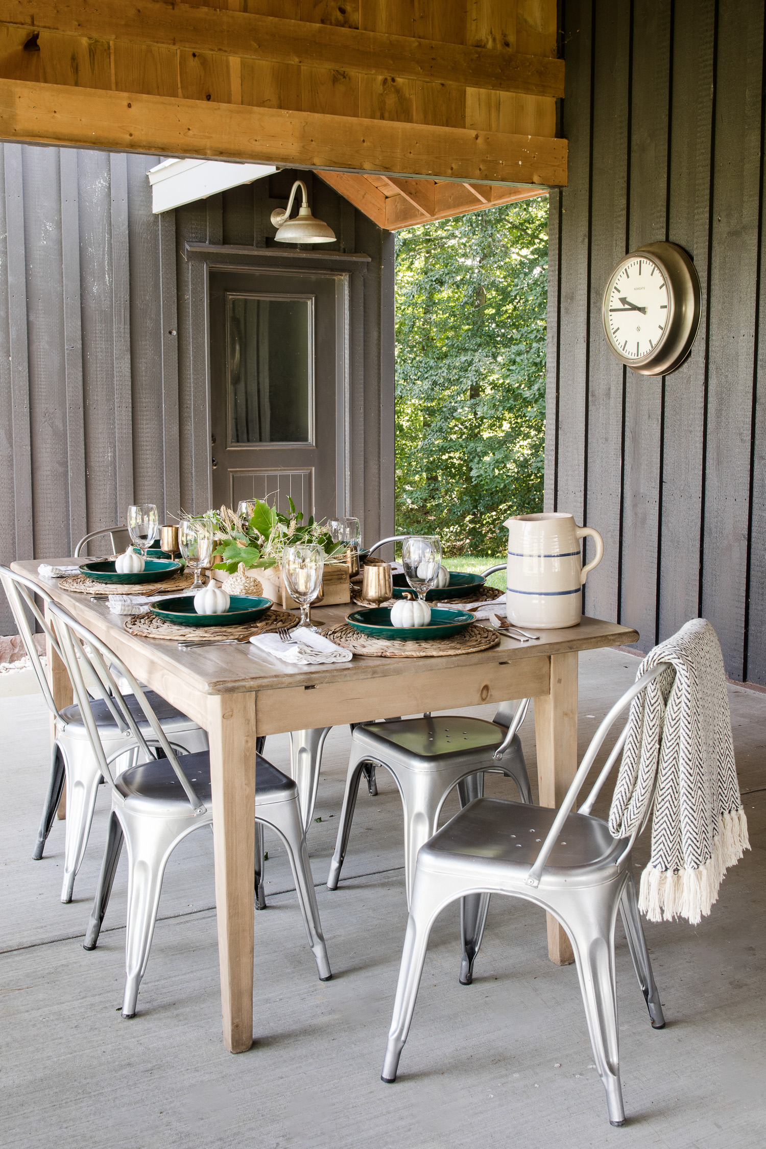 black barndominium with wood board and batten.Wood table on back patio with fall decor