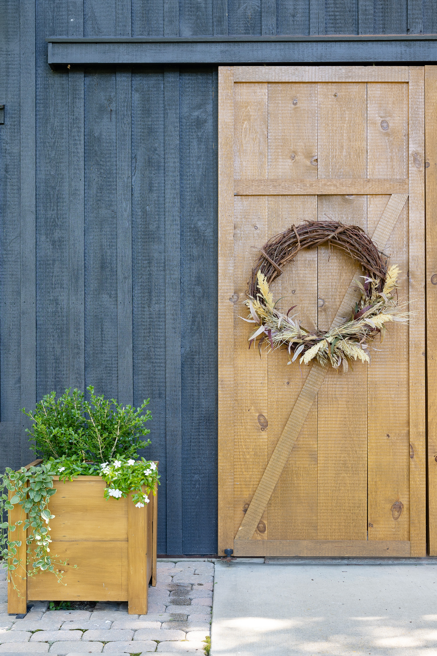 wood barn doors with fall wreaths and planter boxes with plants. 