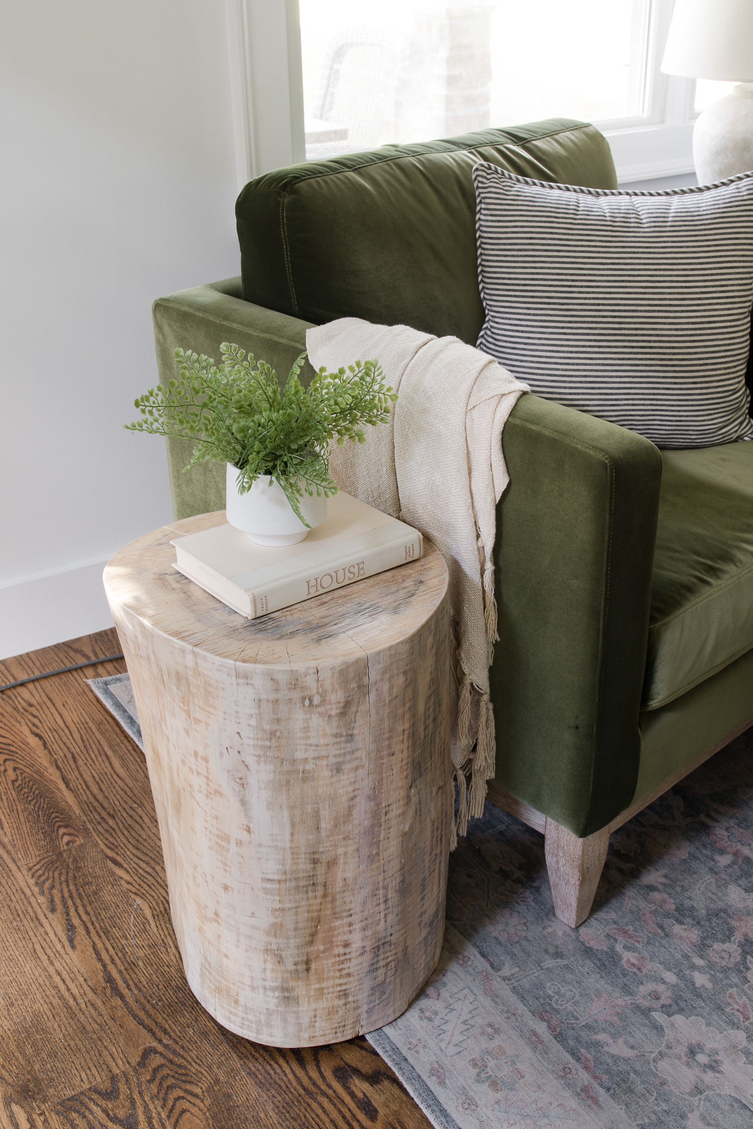 tree stump side table sitting next to green velvet chair in living room
