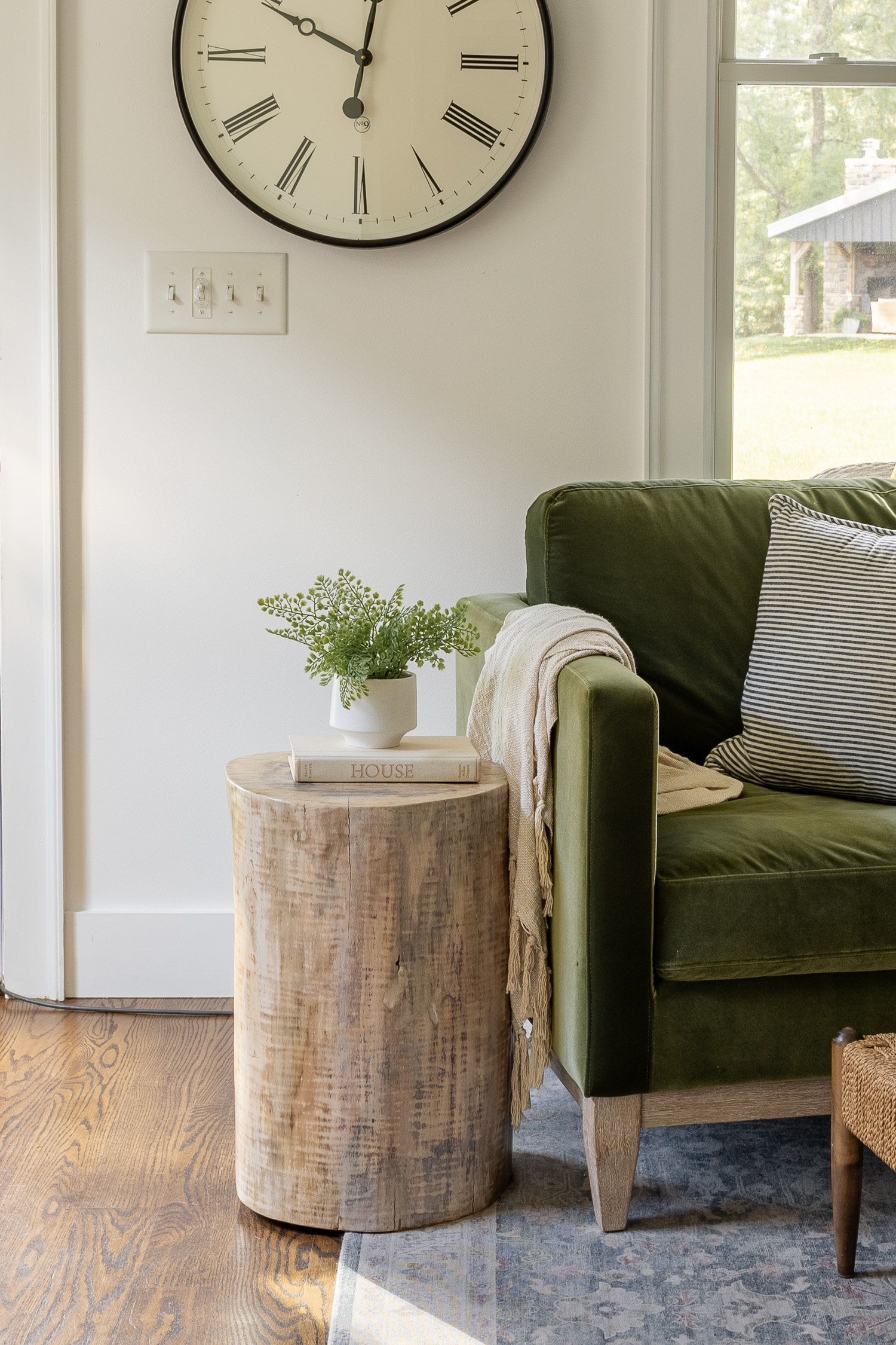 tree stump side table sitting next to green velvet chair in living room
