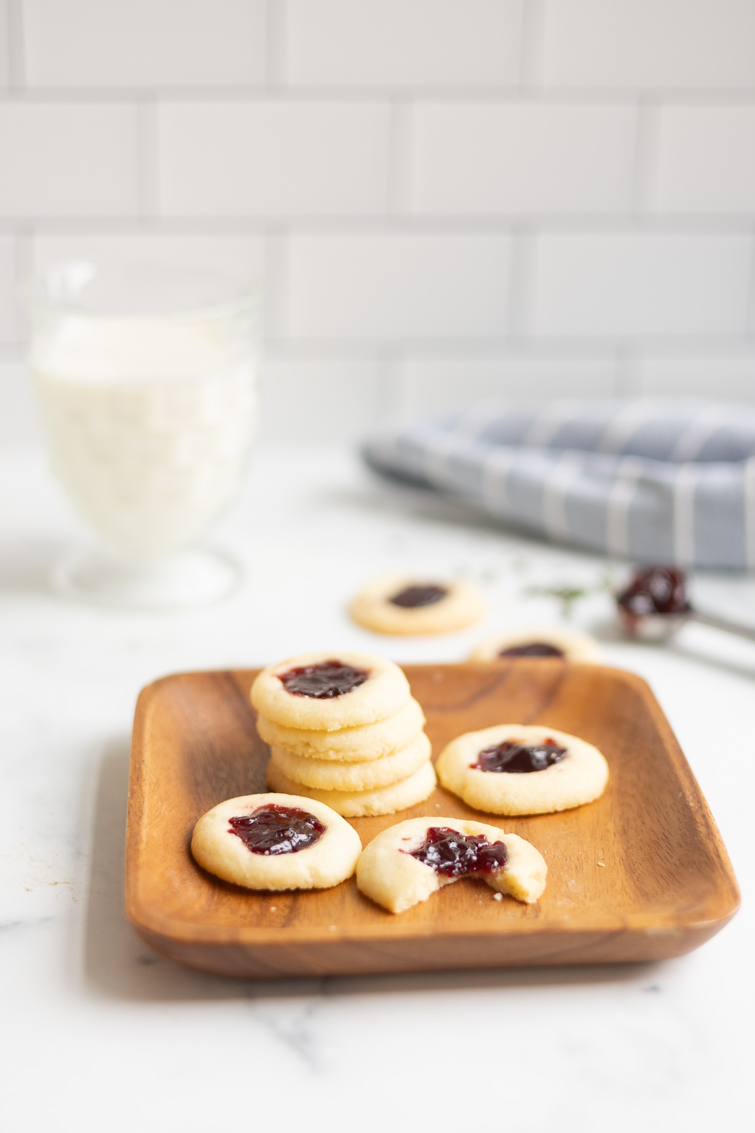 Thumbprint cookies on wood tray with glass of milk