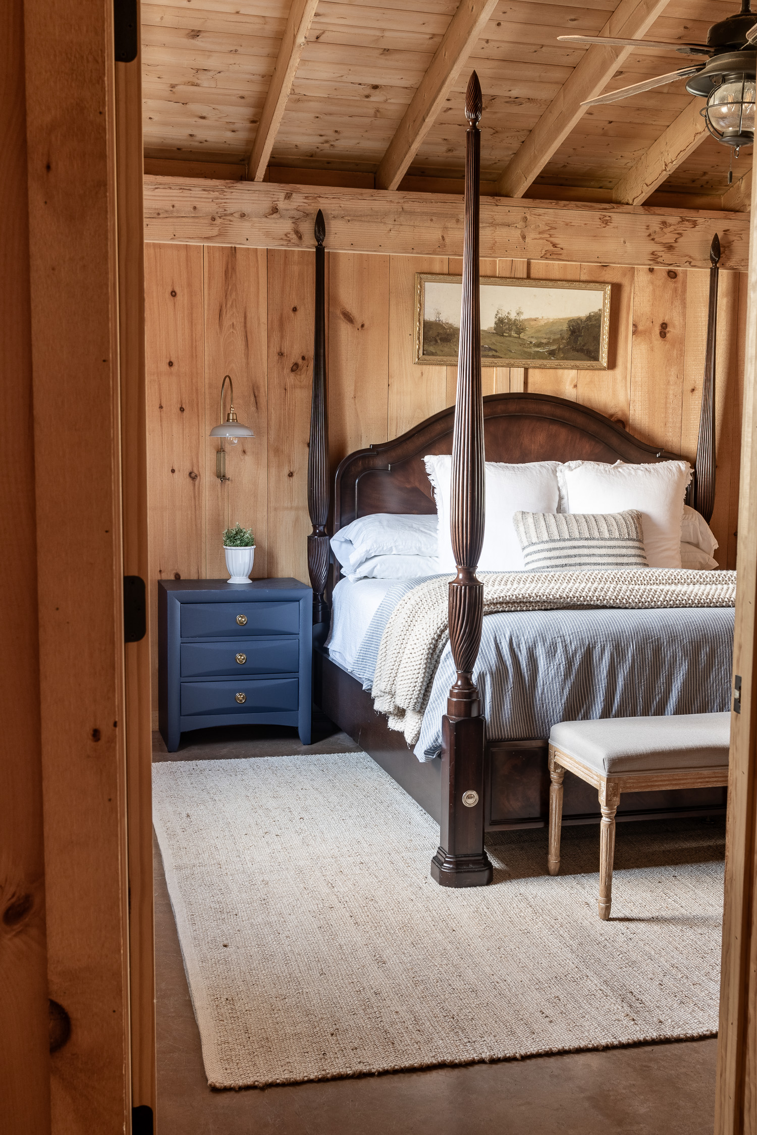 primary bedroom with post bed, blue nightstand and jute rug