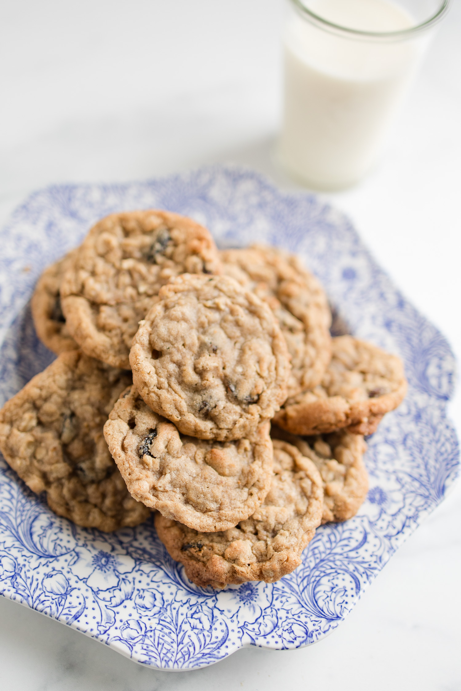 oatmeal cookies on blue floral plate with glass of milk