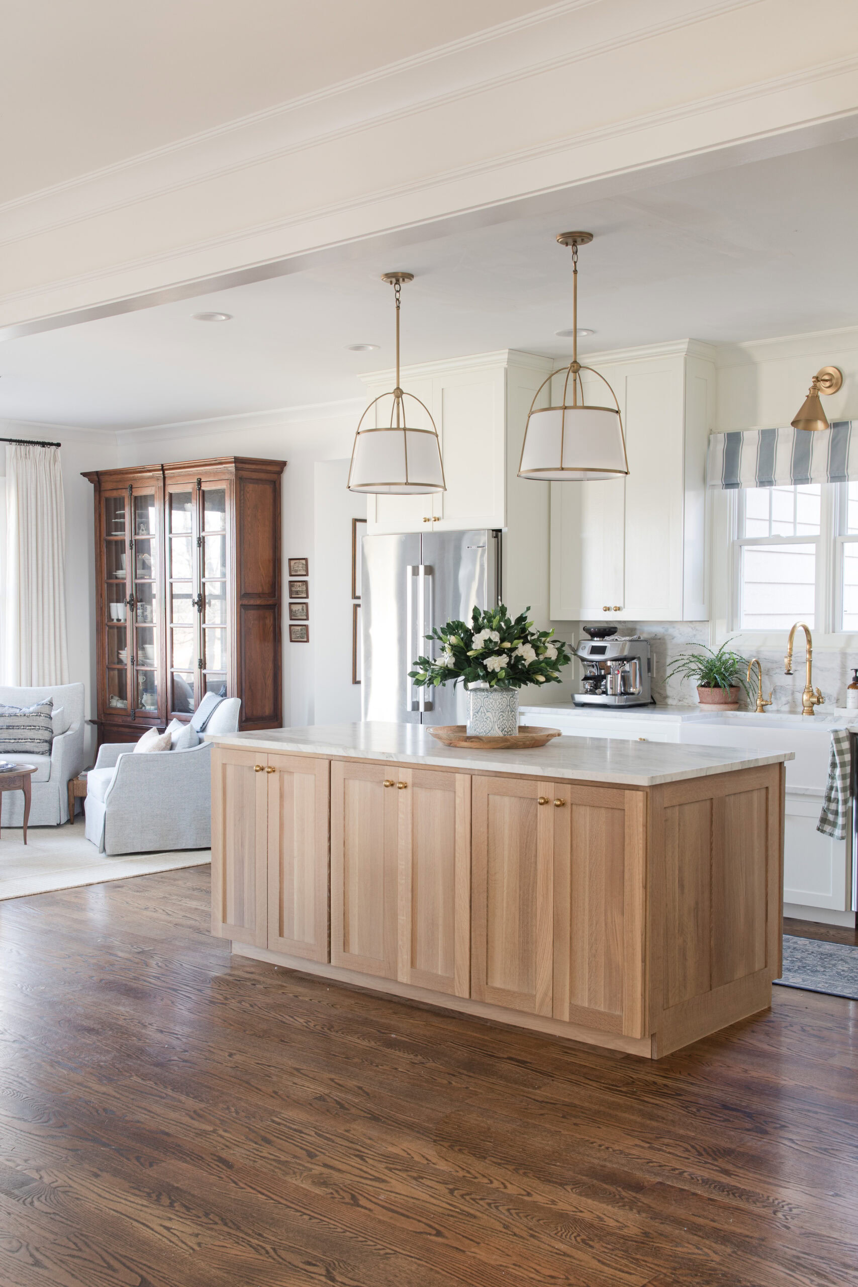 white and wood kitchen with lights and sitting room next to the kitchen