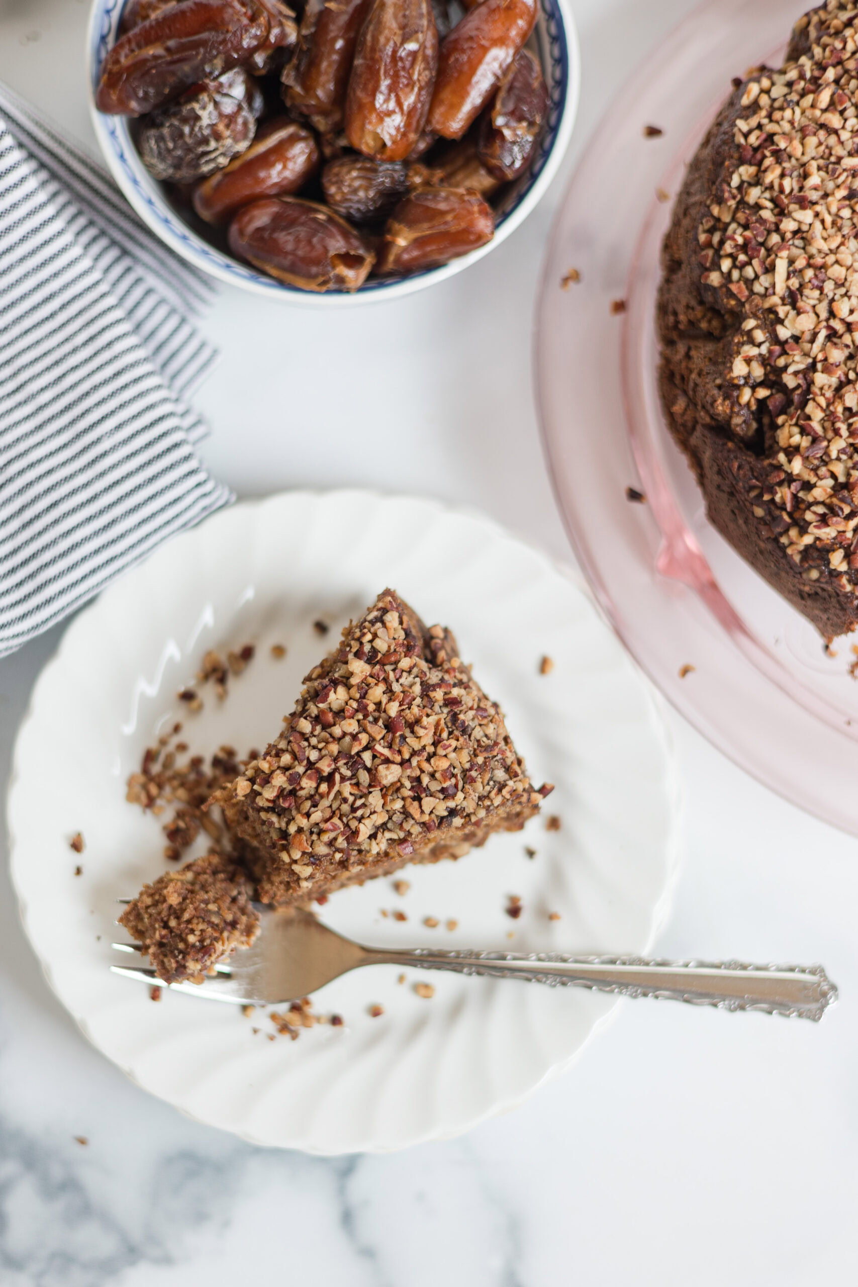 slice of date cake on a plate with bowl of dates
